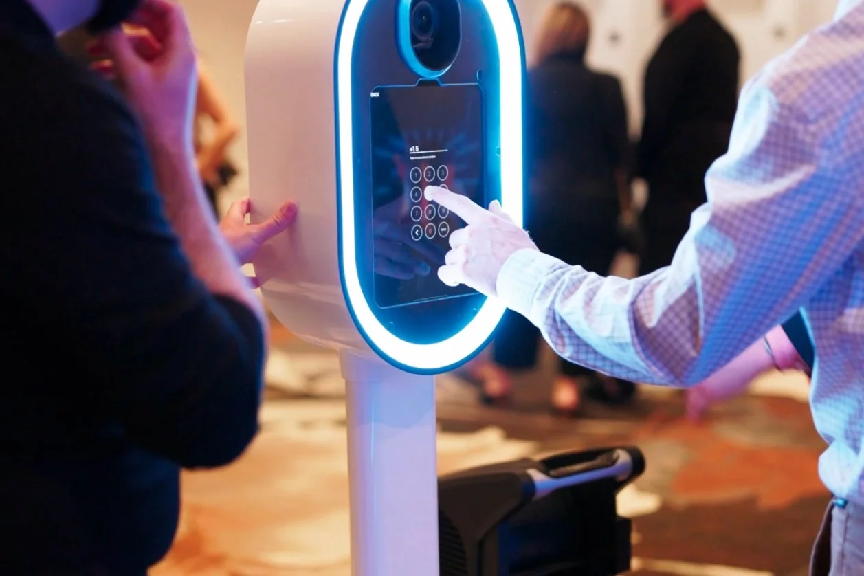 A person using a touchscreen kiosk with a futuristic design and blue lighting at an indoor event.