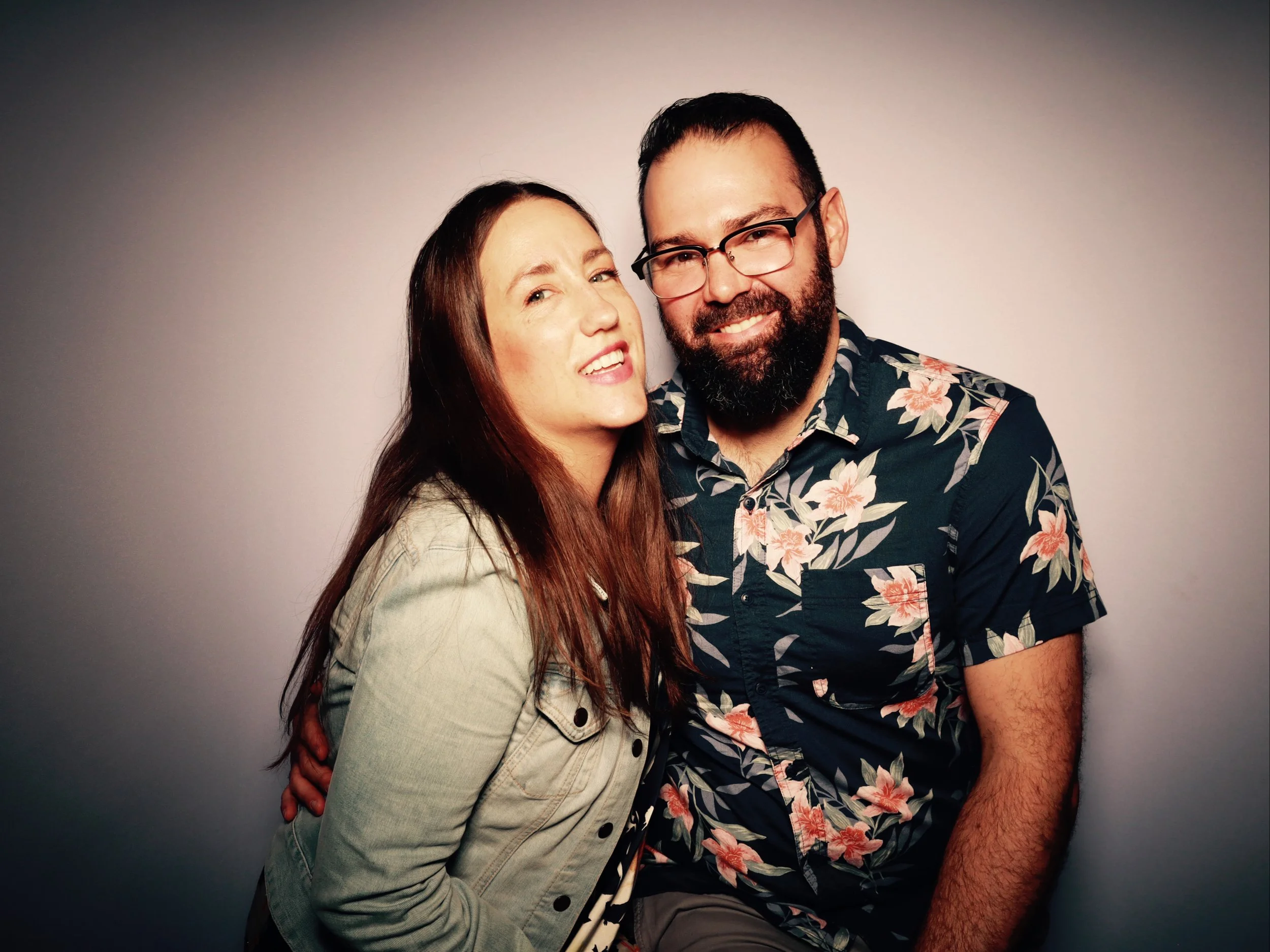 A woman and man smiling and posing together against a plain light background.