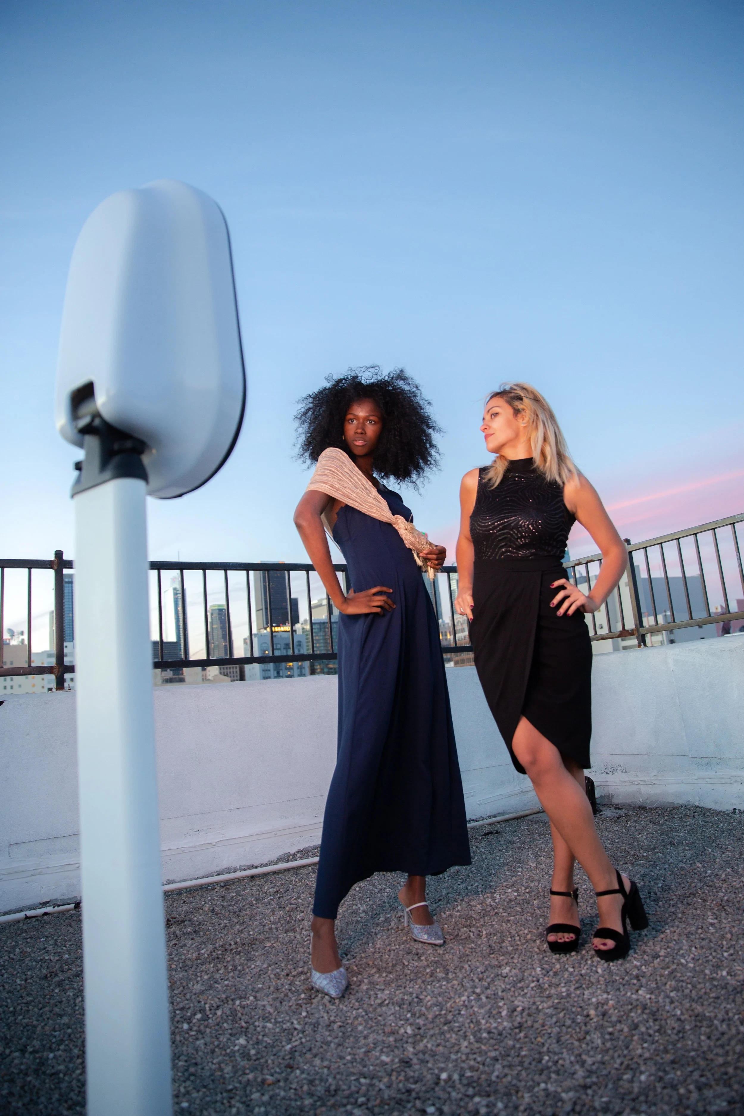 two women posing for a photo on a building terrace in front of a flash co digital photo booth