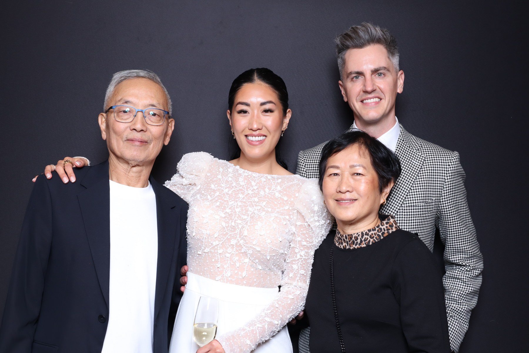 Group of five people at an event, smiling and posing for the camera, against a dark background.