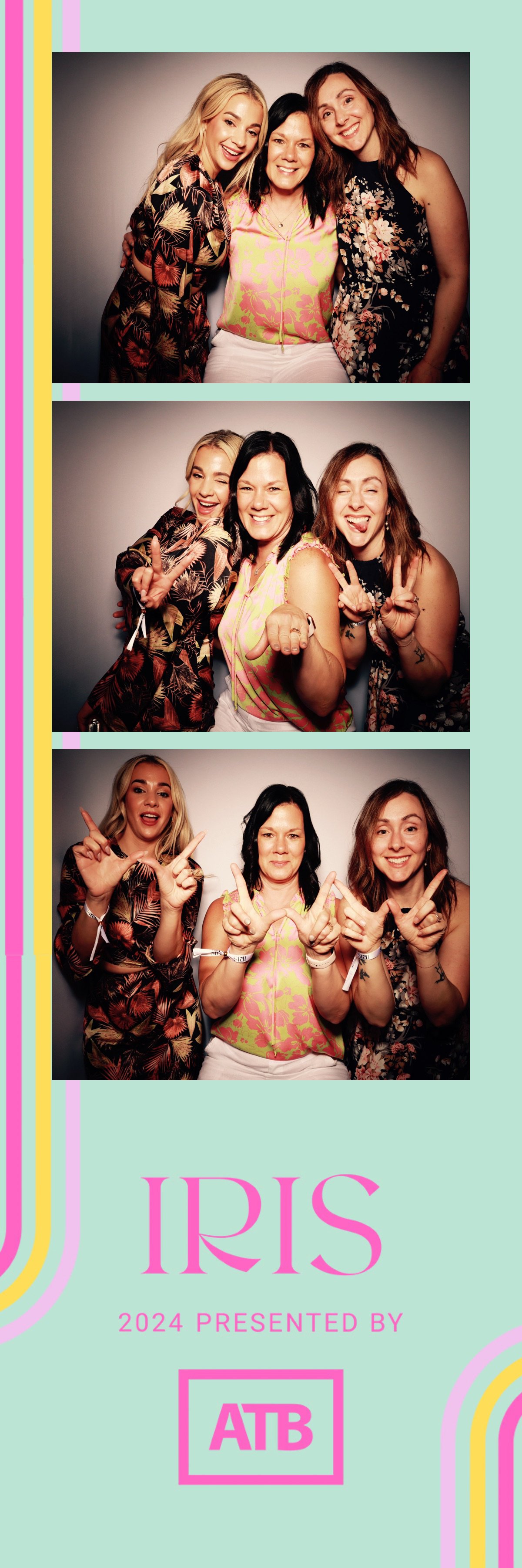 Three women in floral clothing smiling and making peace signs in front of a gray background at the Iris event, 2024, sponsored by ATB.