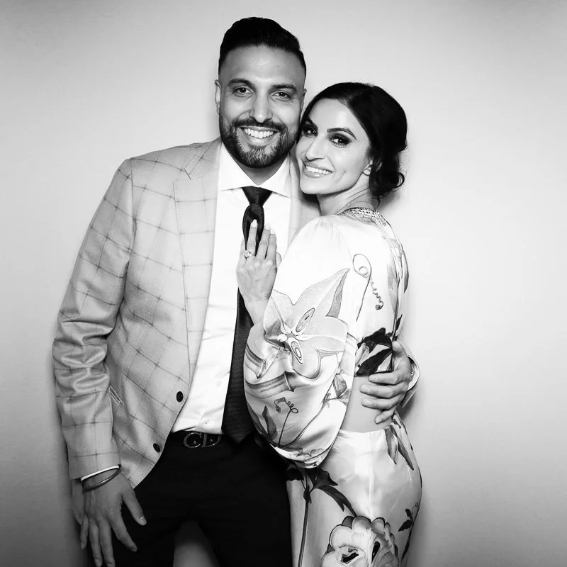A smiling couple dressed in formal attire posing together indoors.
