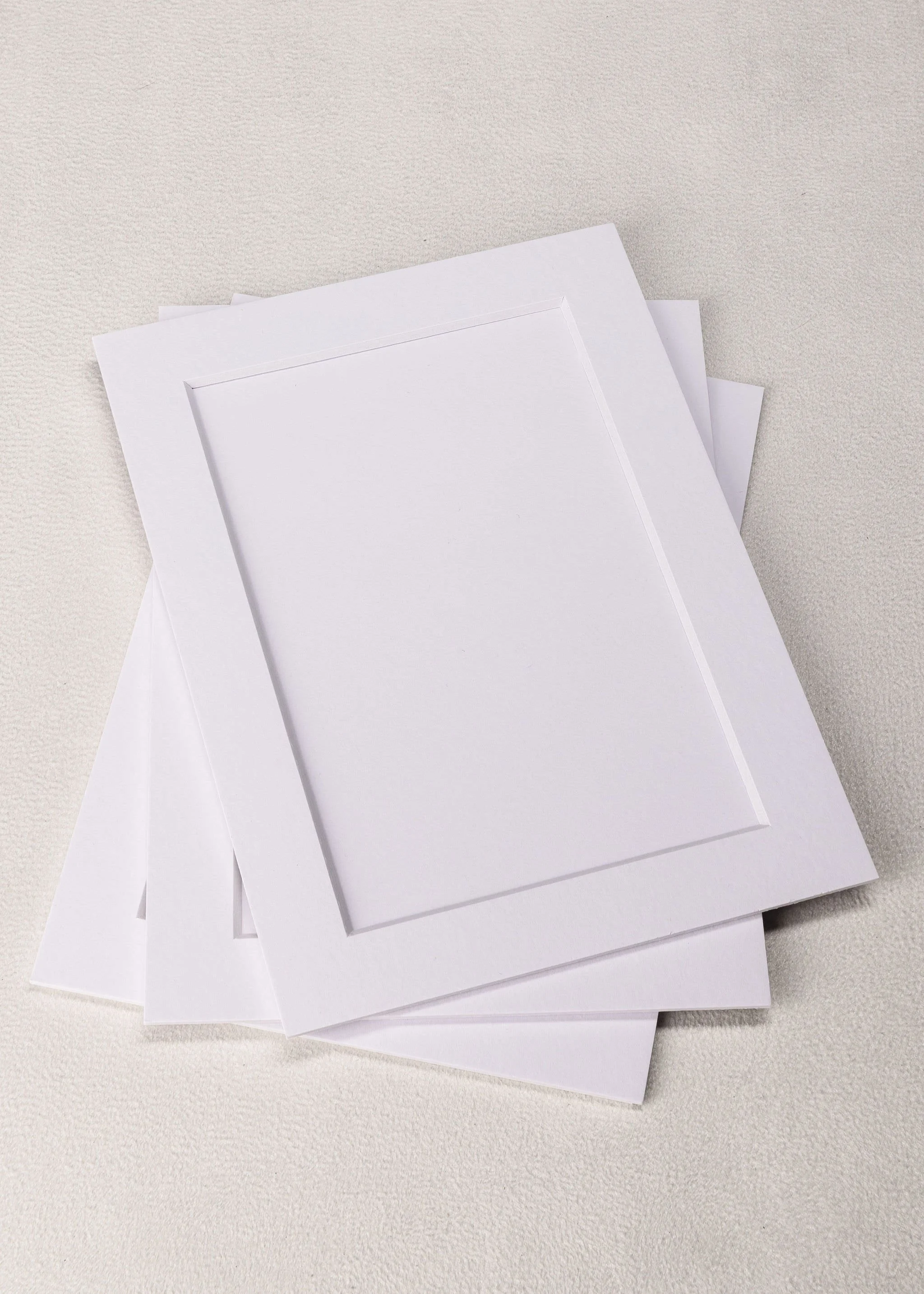 Stack of blank white picture frames on a light-colored surface.