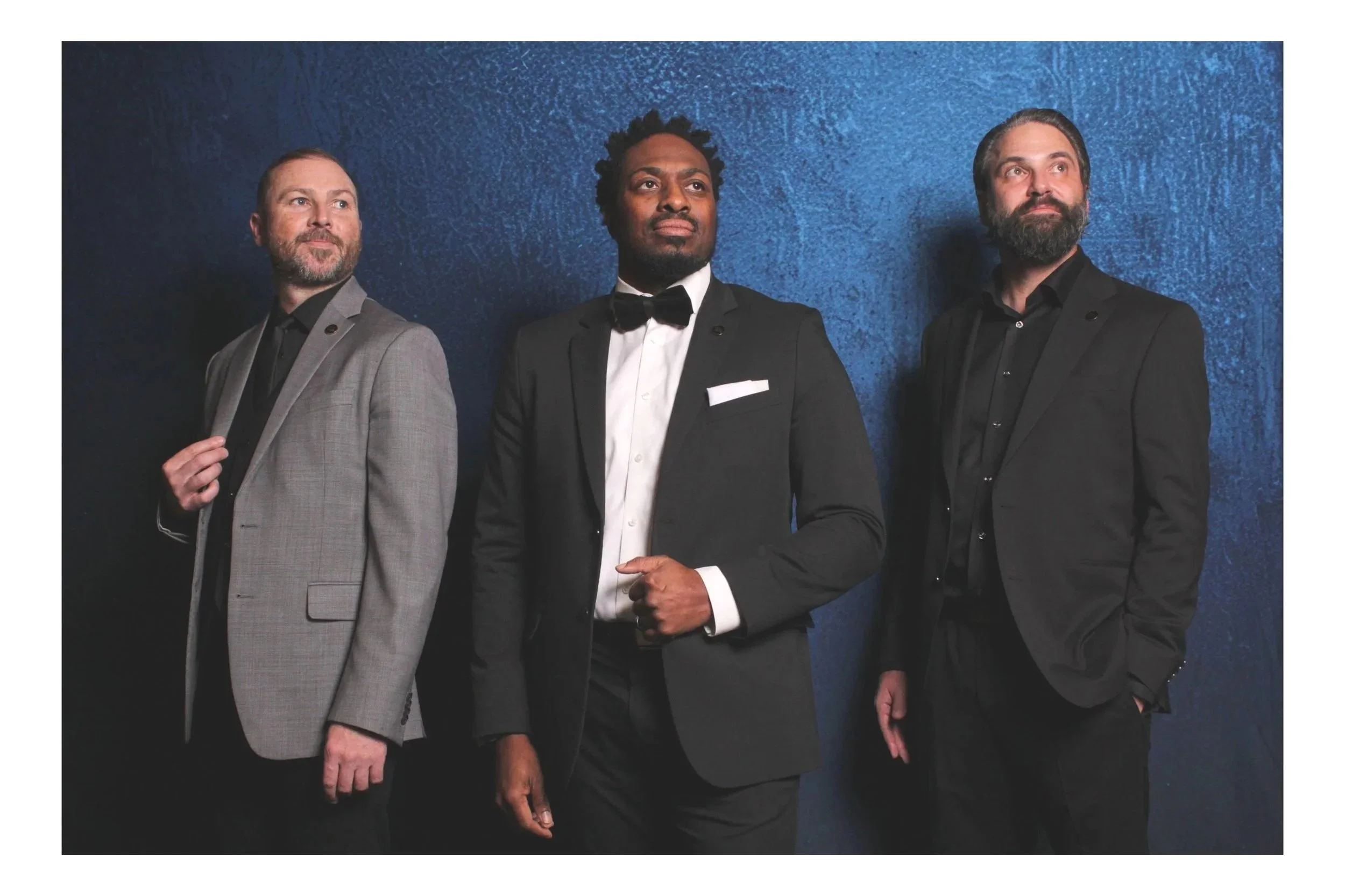 three men in suits posing for a photo in a studio photo booth