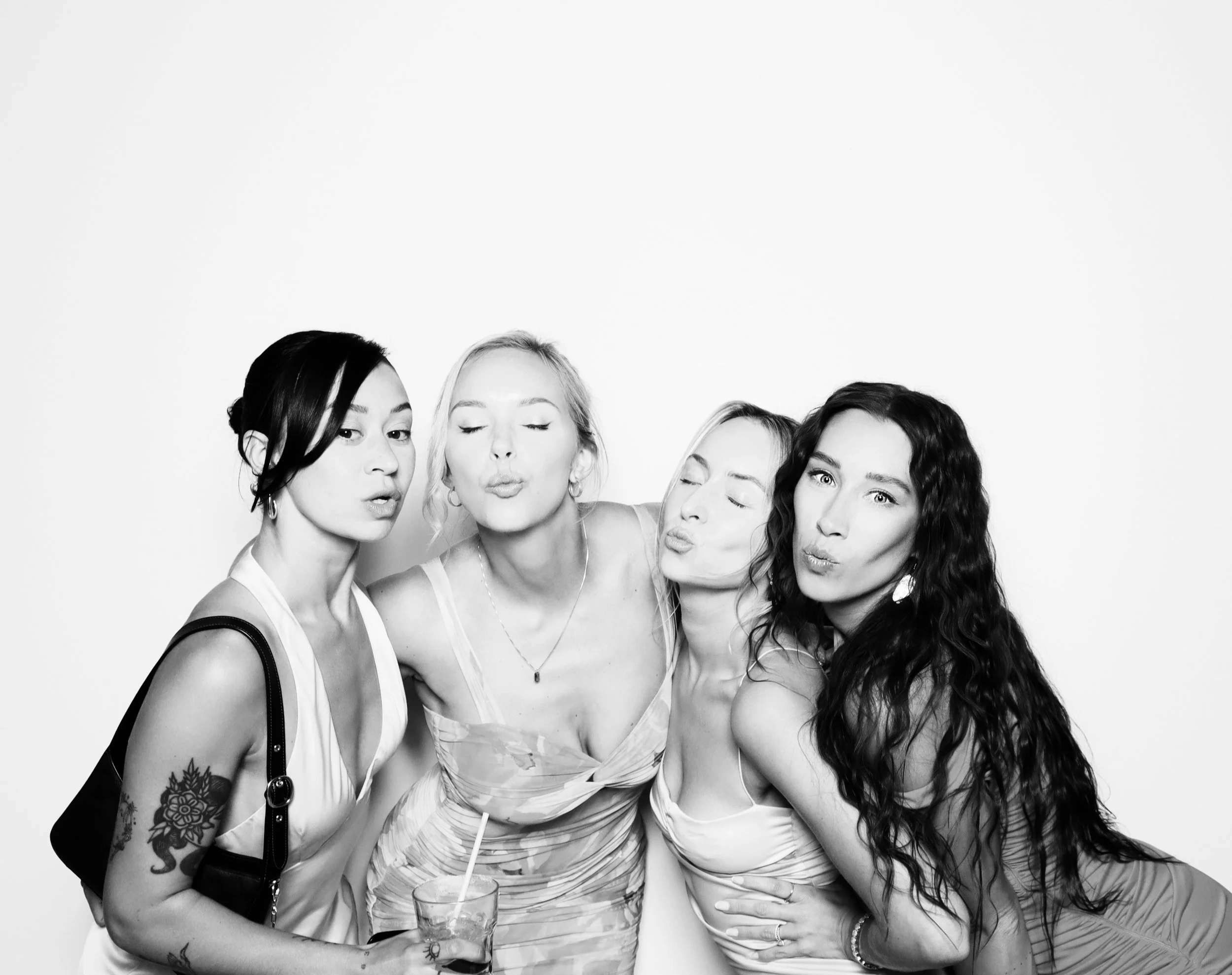 Four women posing together in a photo booth, making kissy faces.