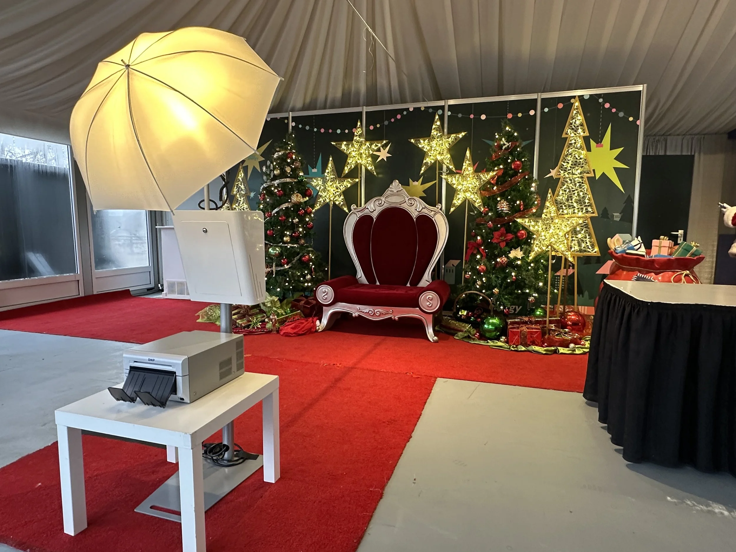 a photobooth setup in front of a holiday set and santas chair