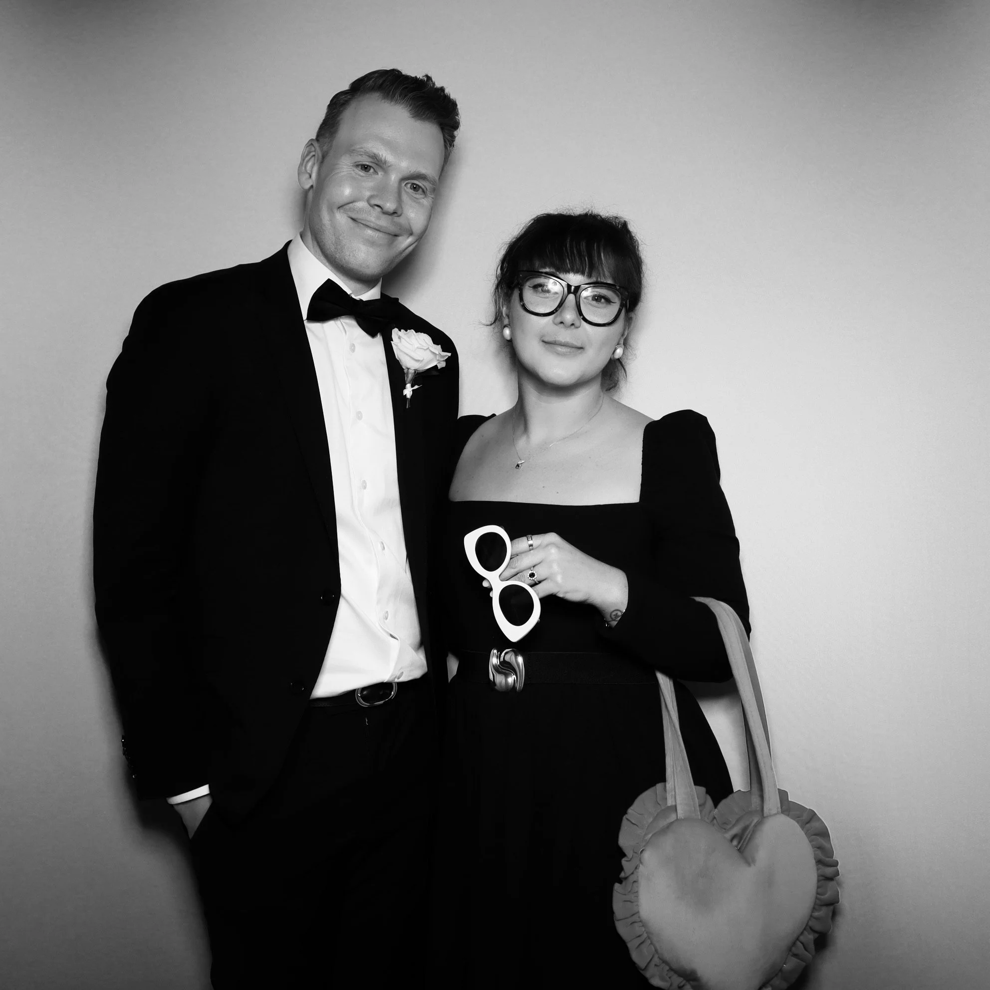 A black-and-white photo of a man and woman dressed formally, smiling and posing together at an event.