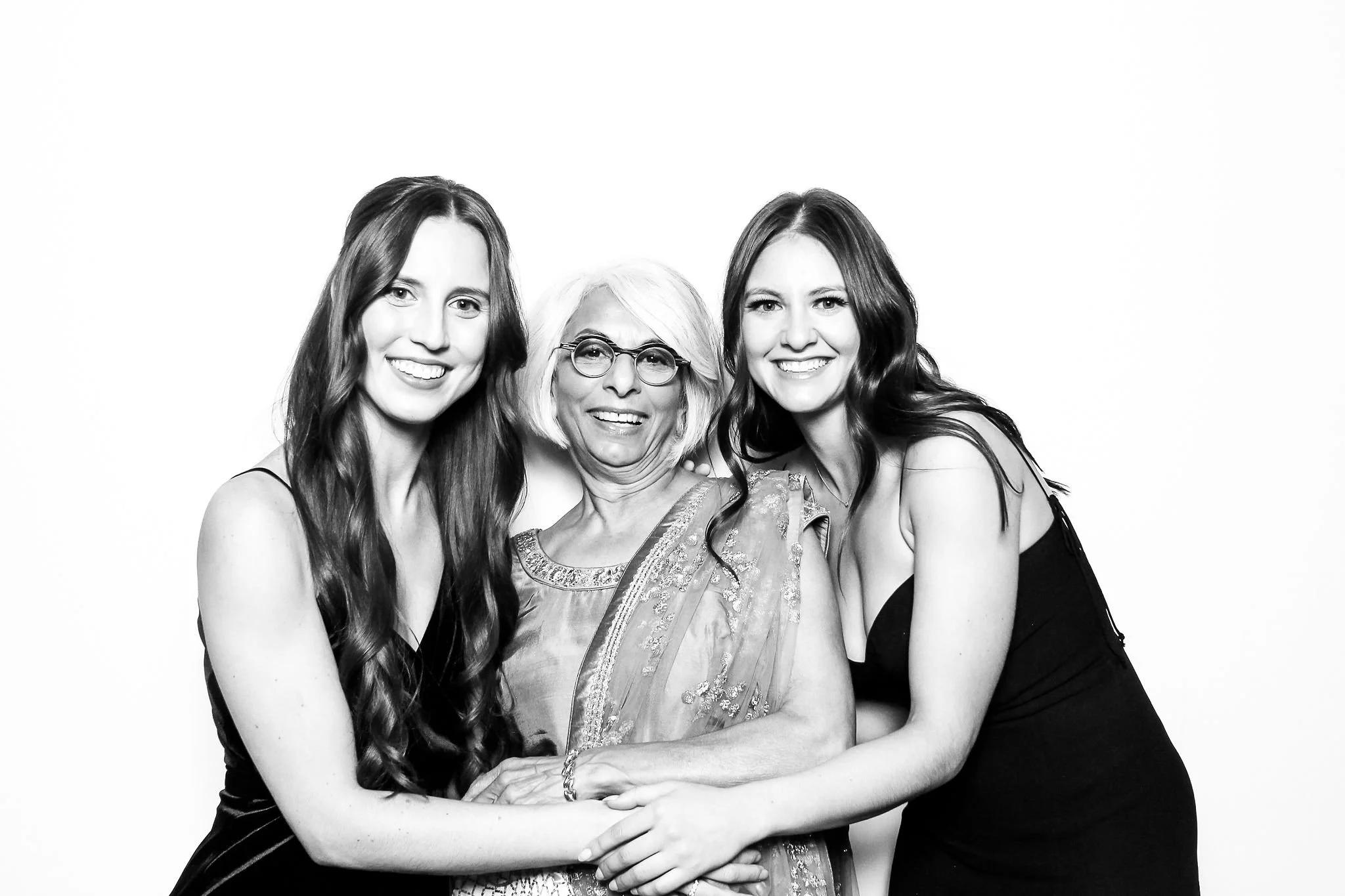 Three women smiling and hugging each other in black and white photo.