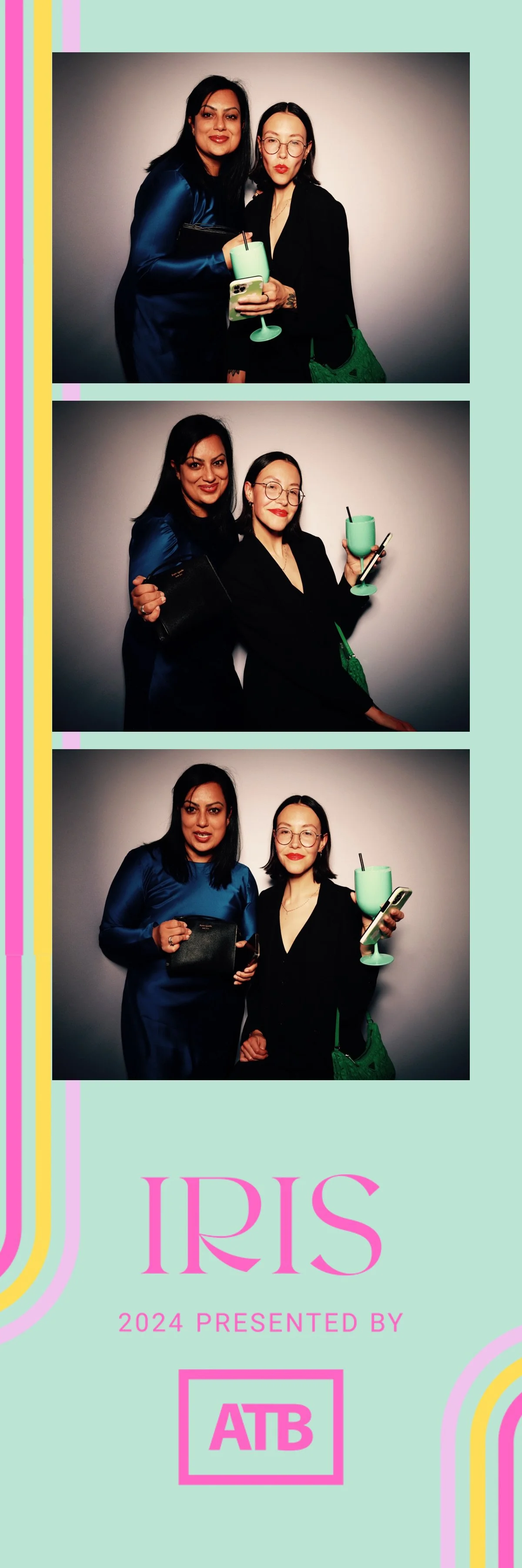Three women posing in a photo booth with drinks. They are dressed in dark and blue outfits, holding phones and clutches, with colorful drinks in hand.