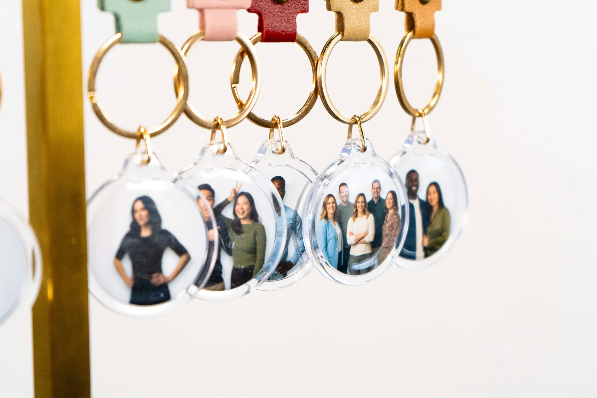 A display of keychains with clear circular pendants featuring group photos of diverse people.