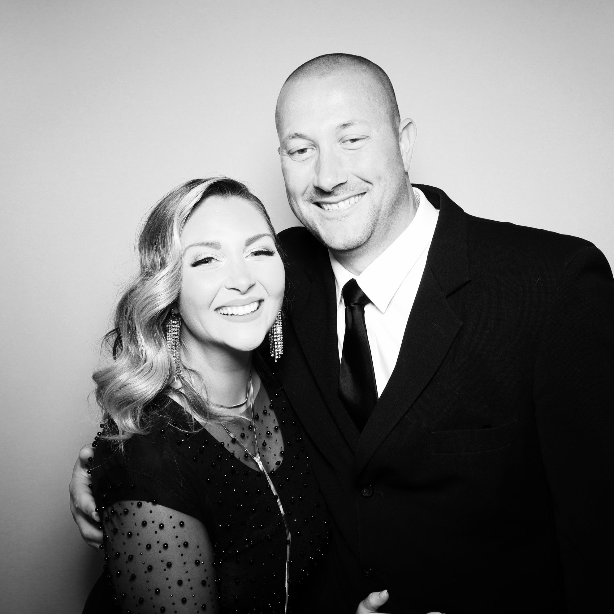 Black and white photo of a smiling man and woman dressed in formal attire, posing closely together.