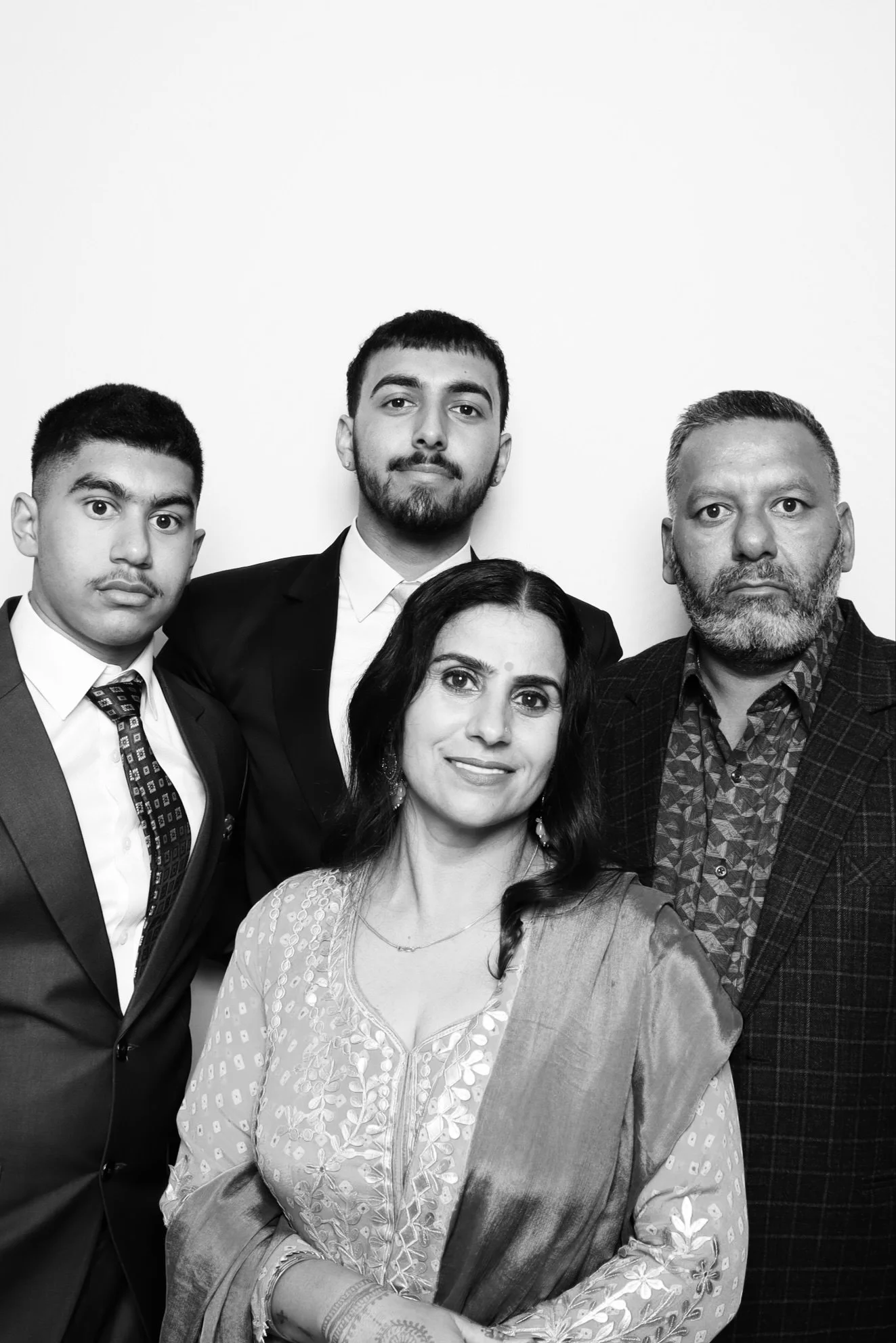 A black and white portrait of five diverse adults, three men and two women, dressed in formal attire, standing against a plain background.