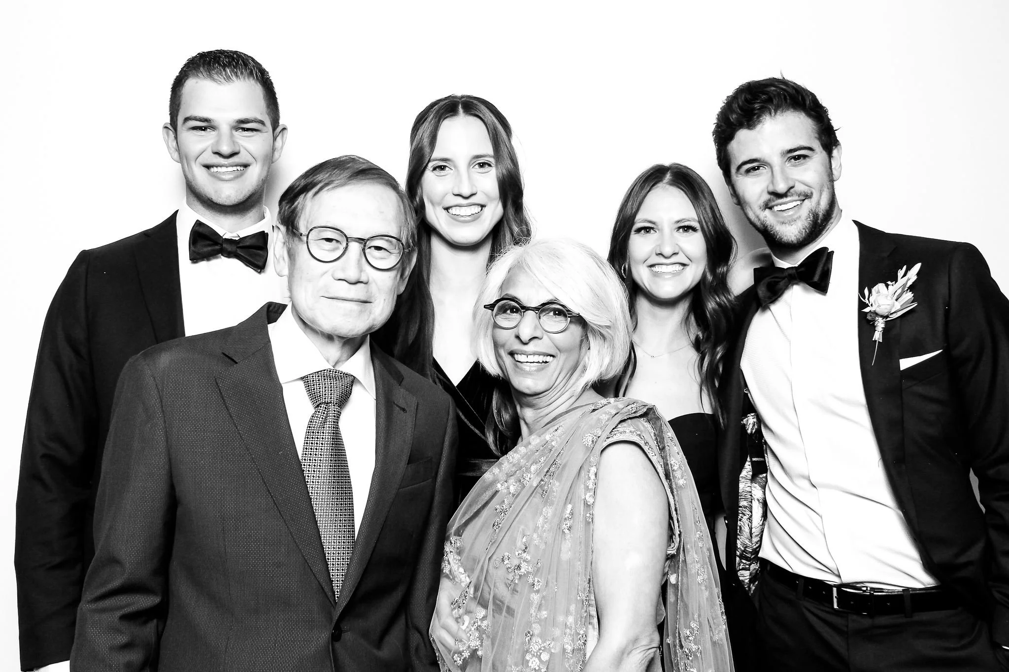 Black and white photo of six people dressed in formal attire, smiling, at a celebration or event.