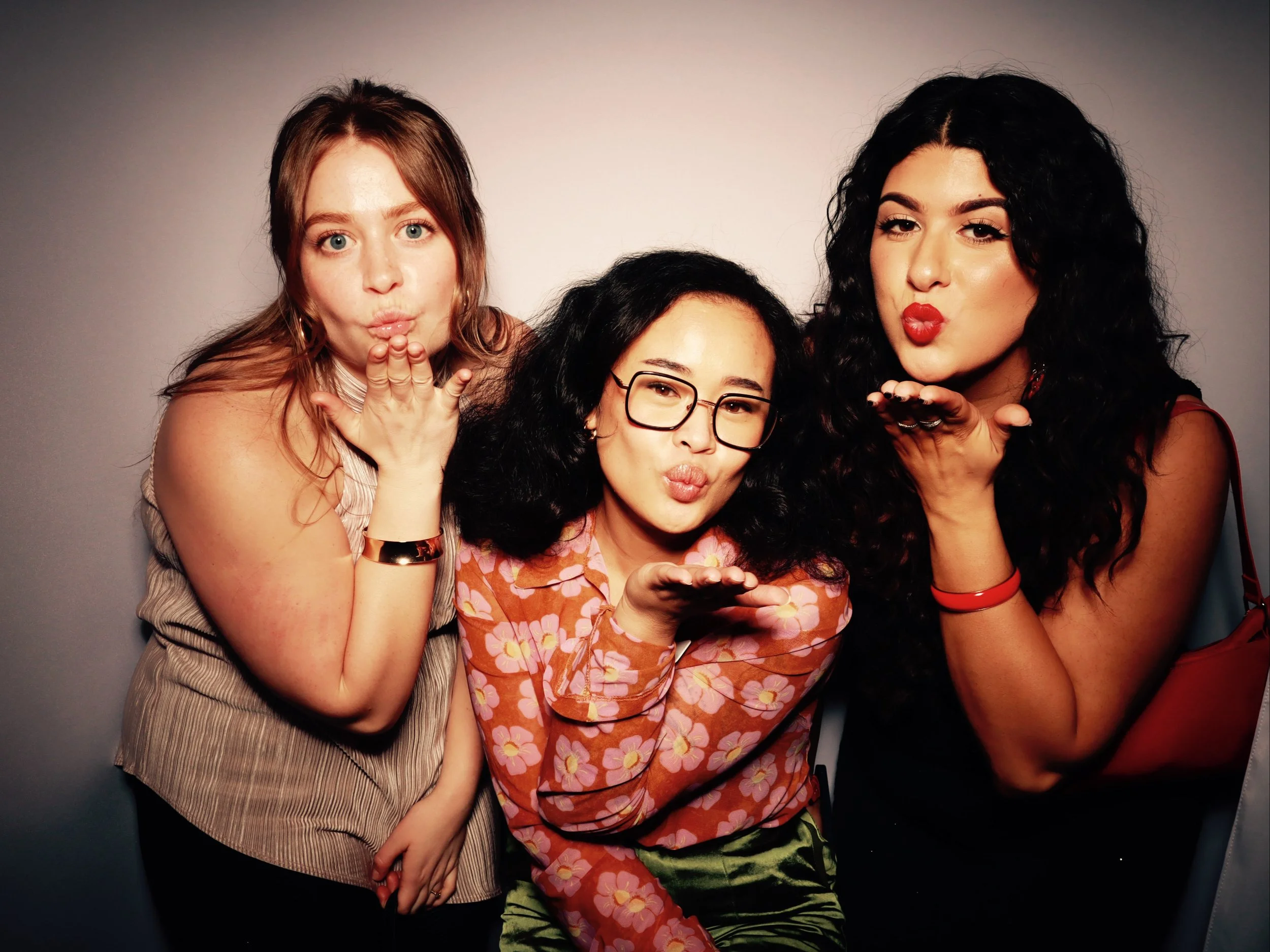 Three women blowing kisses and making playful faces at the camera.