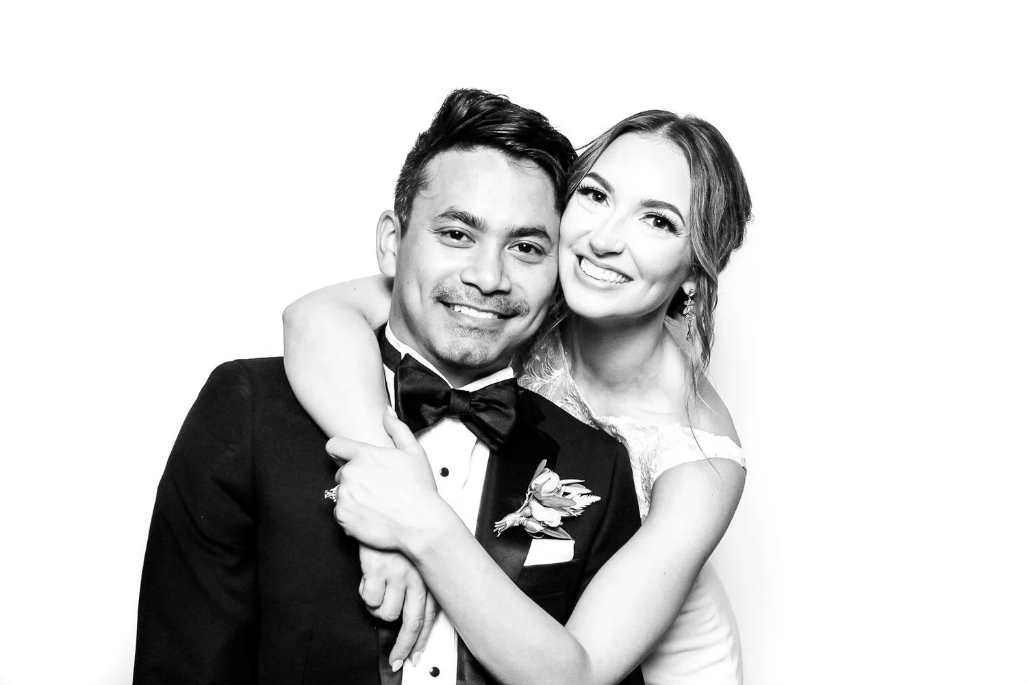 Black and white photo of a happy couple in wedding attire, embracing each other and smiling.