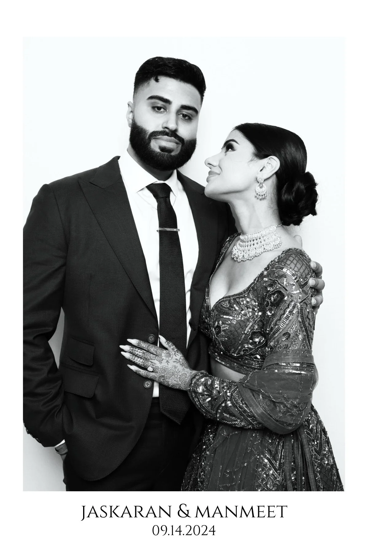 Black and white wedding photo of a couple, with the man in a suit and tie and the woman in an ornate dress with jewelry, looking at each other affectionately, with text indicating the couple's names and wedding date.