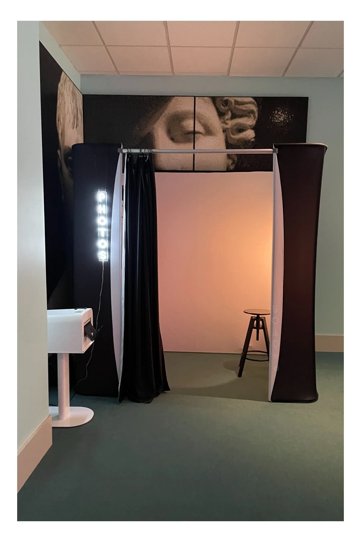 a vintage photo booth enclosure with neon sign and printer setup at a wedding