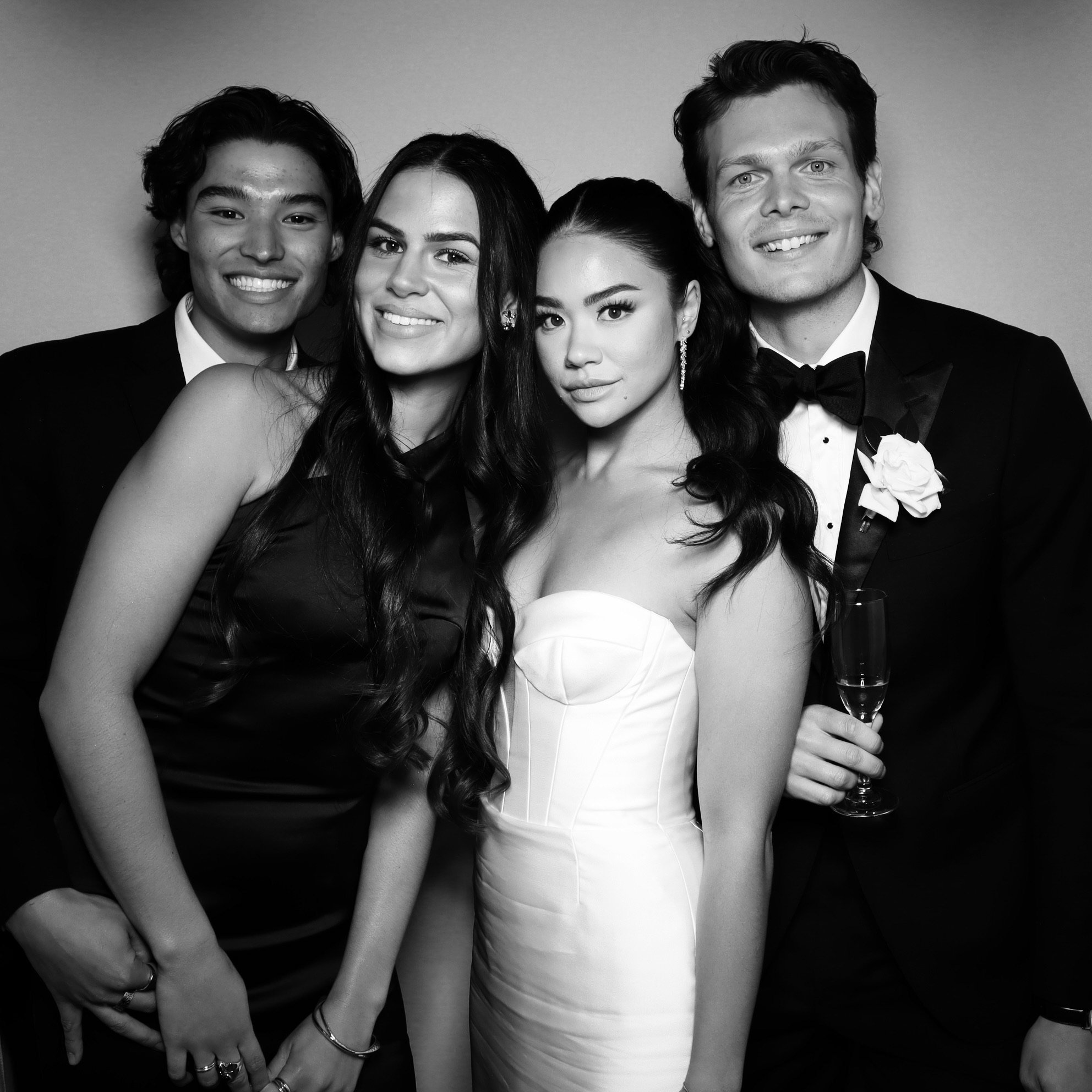 Four young adults dressed in formal attire at a celebration or event.