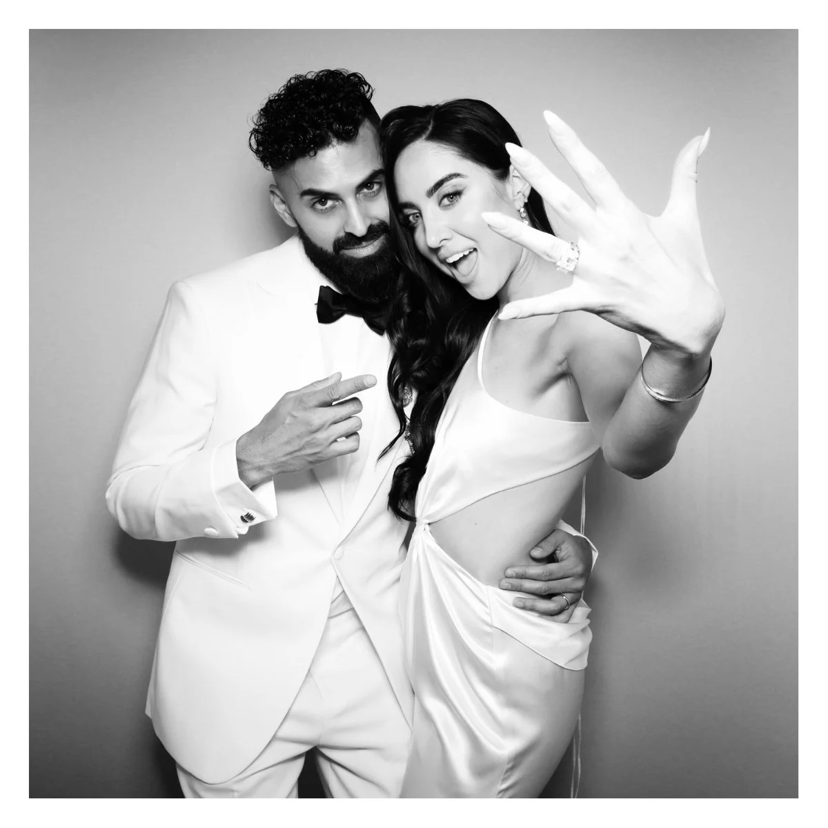 a bride and groom in a vintage photo booth showing off their new wedding rings