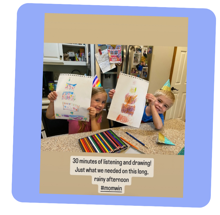 Two smiling children with party hats on proudly hold up the drawings they just made. There are colored pencils on the table.