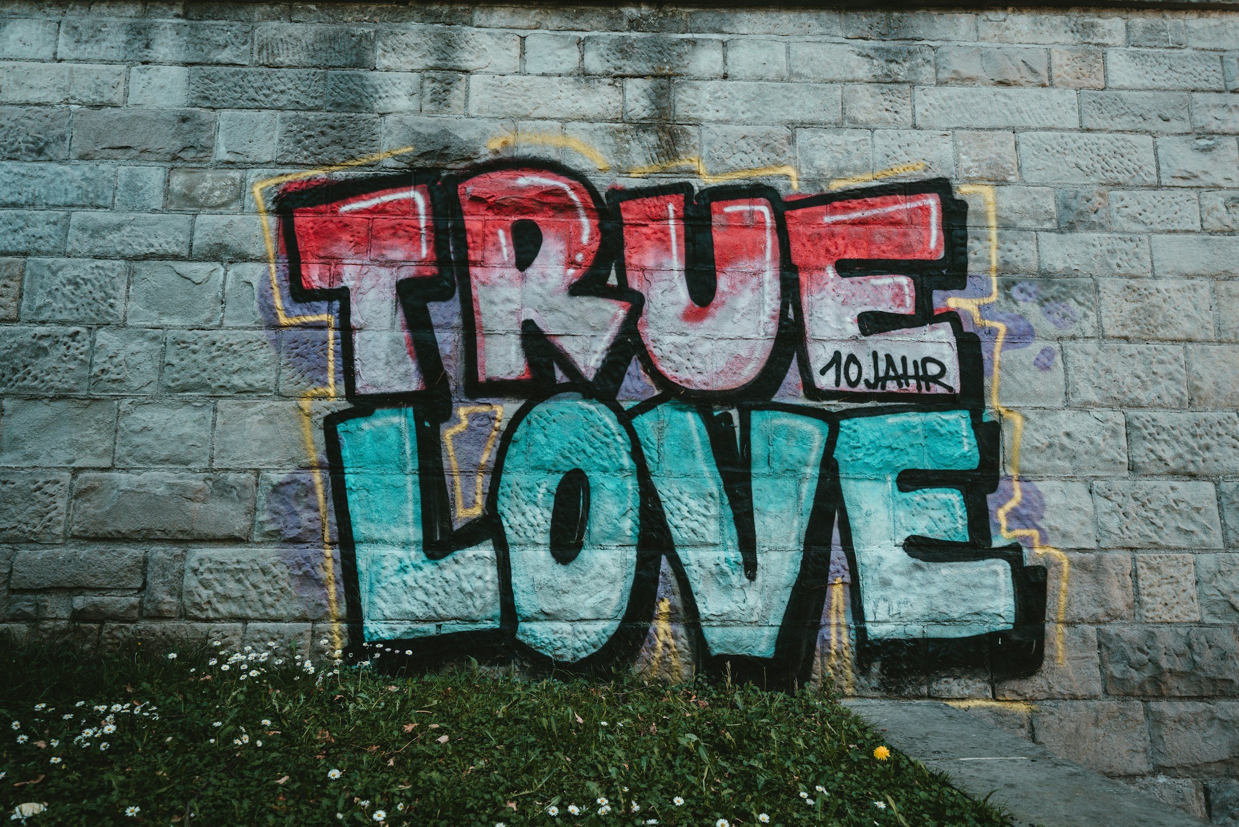 Graffiti on a brick wall with the word "TRUCE" written in bold, colorful letters, with the phrase "10JAH" next to it, and the word "LOVE" underneath.