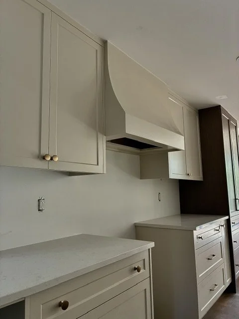 Empty kitchen with white cabinets, a white range hood, and a white countertop.