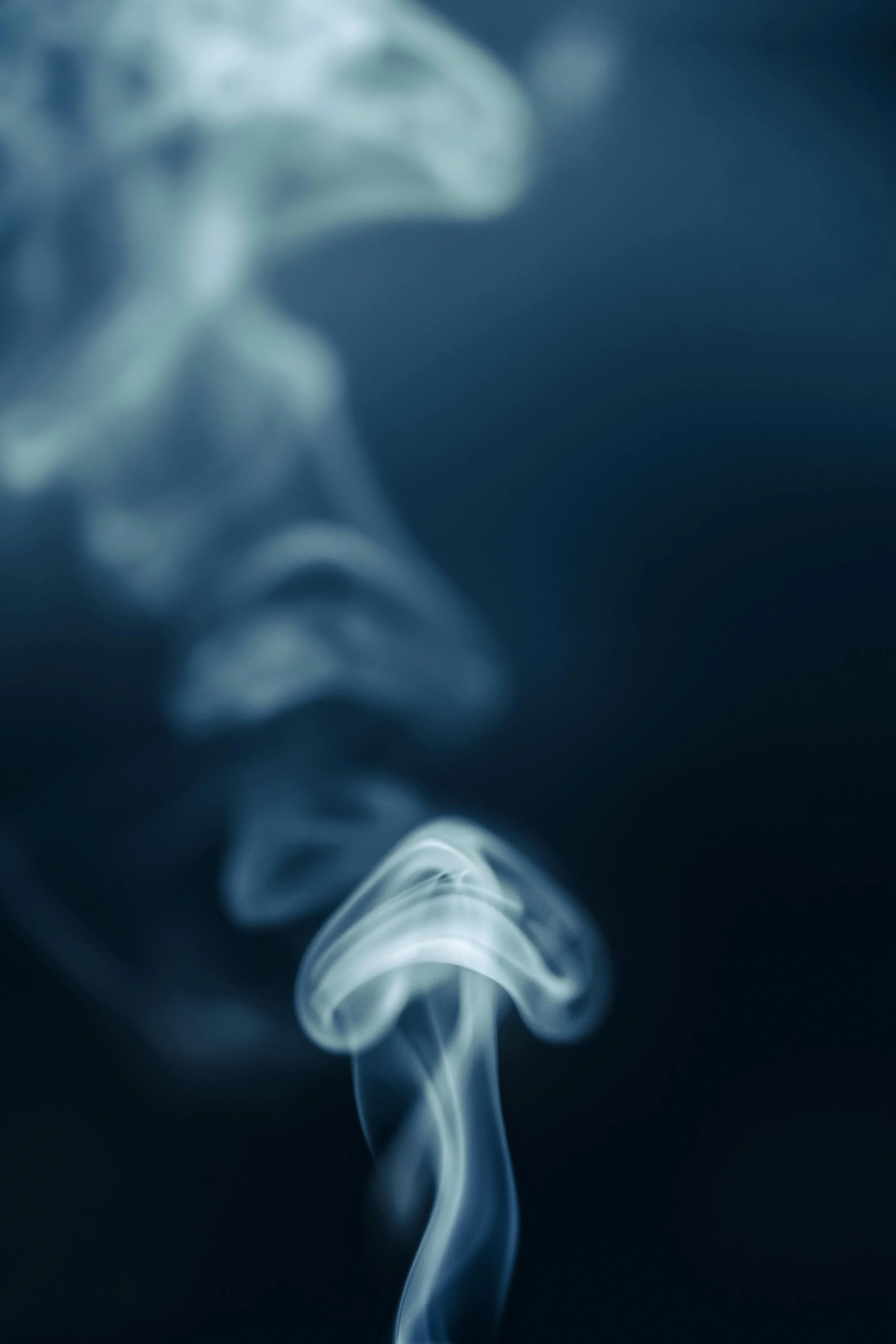 Close-up of smoke curling and wisps against a dark background.