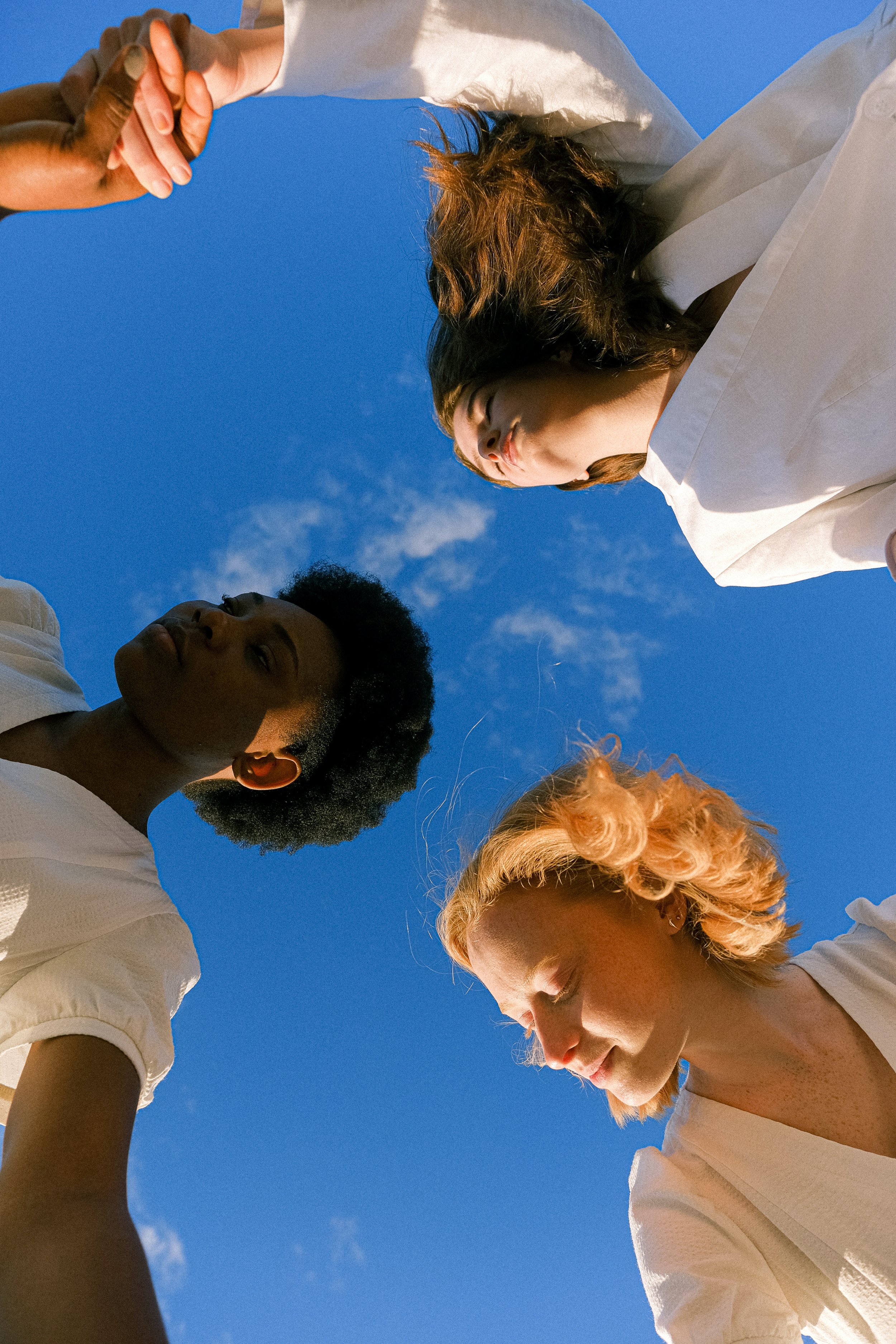 Group of four people looking down at the camera, with a clear blue sky background.