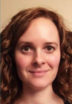 Close-up of a woman with curly red hair and a slight smile.