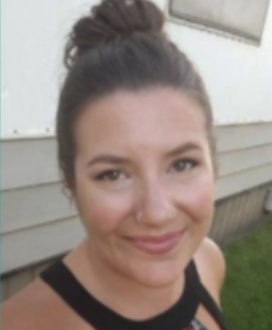 Close-up of a young woman with a bun hairstyle, smiling outdoors in front of house siding.