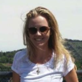Woman with blonde hair wearing sunglasses and a white t-shirt outdoors.