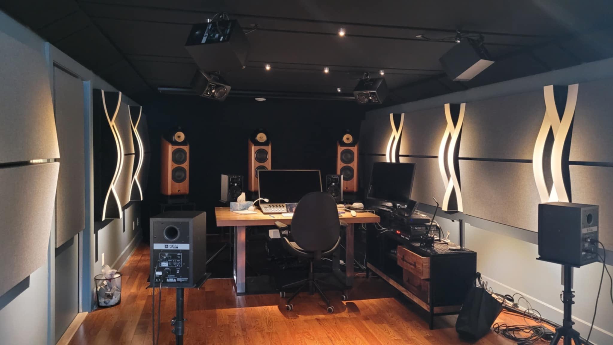 Recording studio with soundproof walls, professional audio equipment, mixing console, computer monitors, speakers, and acoustic panels