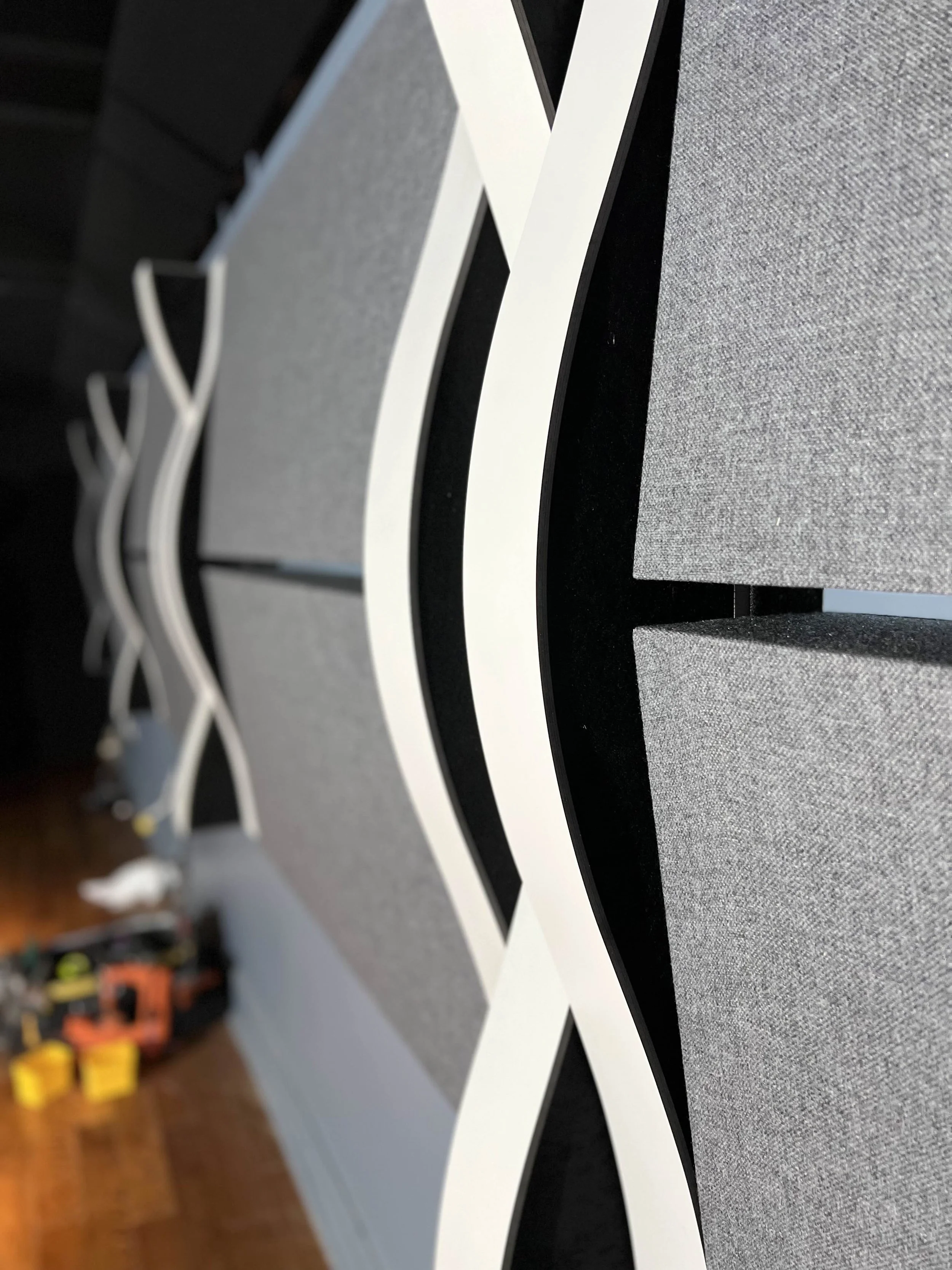 Gros plan d’un panneau mural décoratif noir et blanc moderne et incurvé avec des accents de tissu gris.