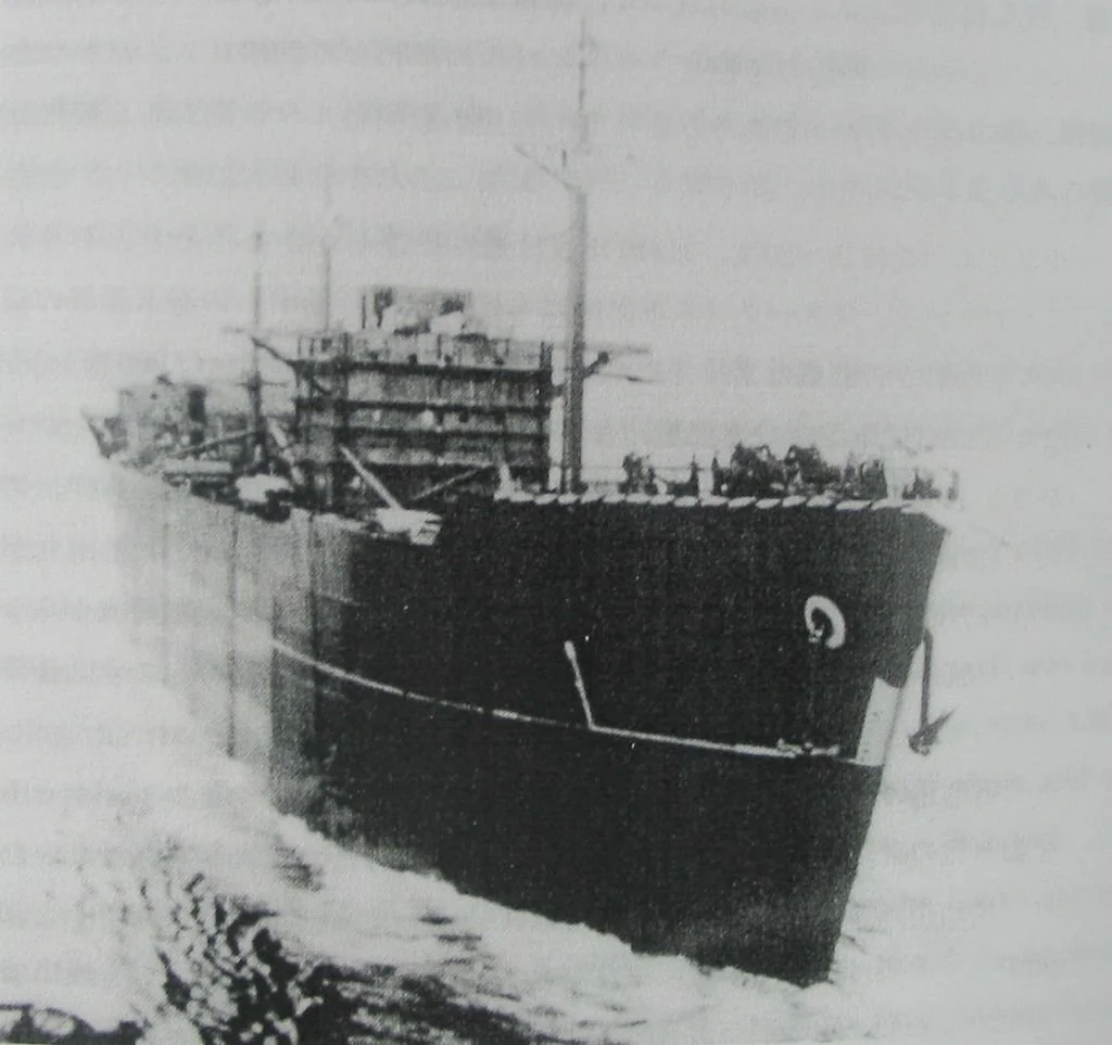 A black and white photo of a large cargo ship sailing in open water.