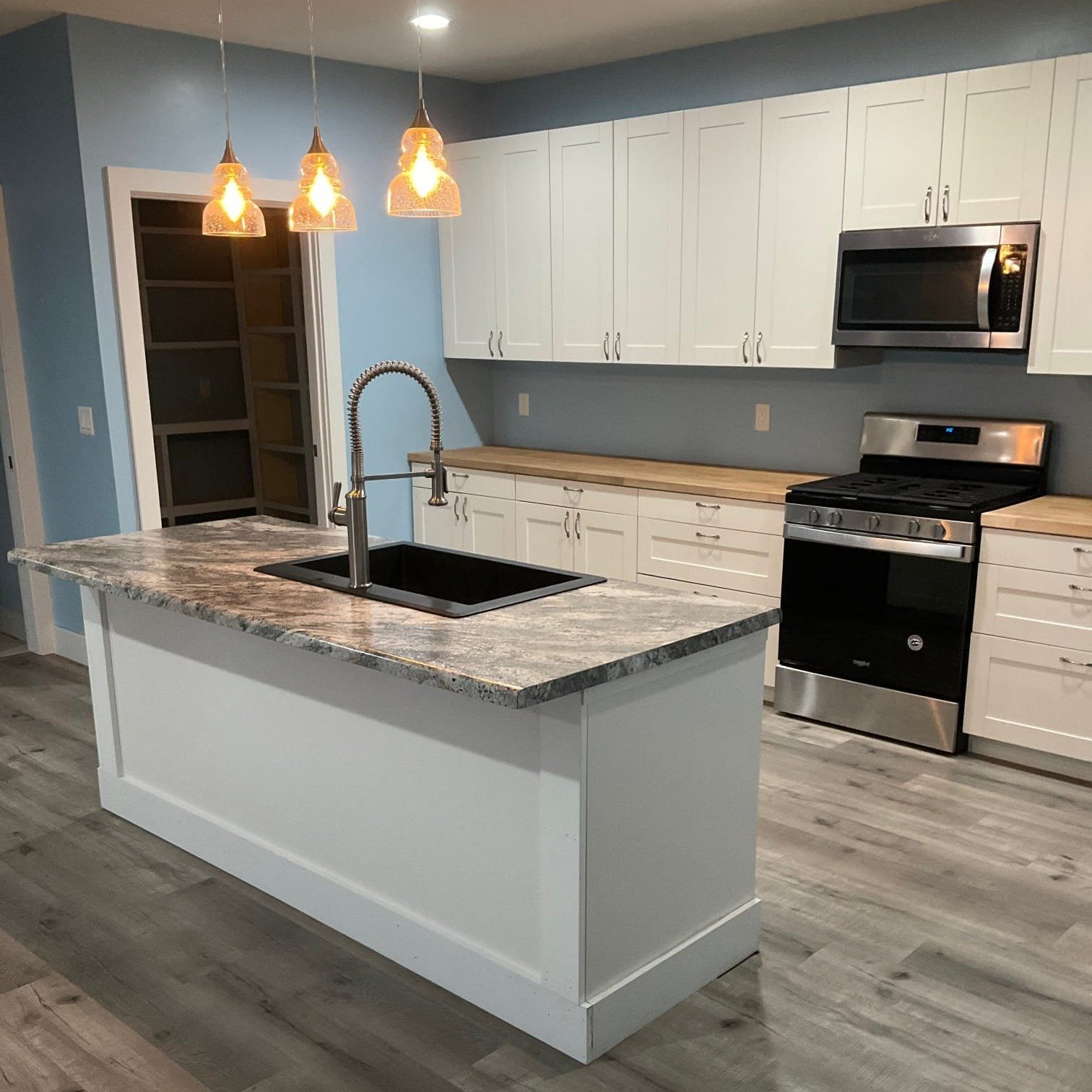 Kitchen remodel with white cabinets, pendant lighting, and gray countertop island – Clearwater FL