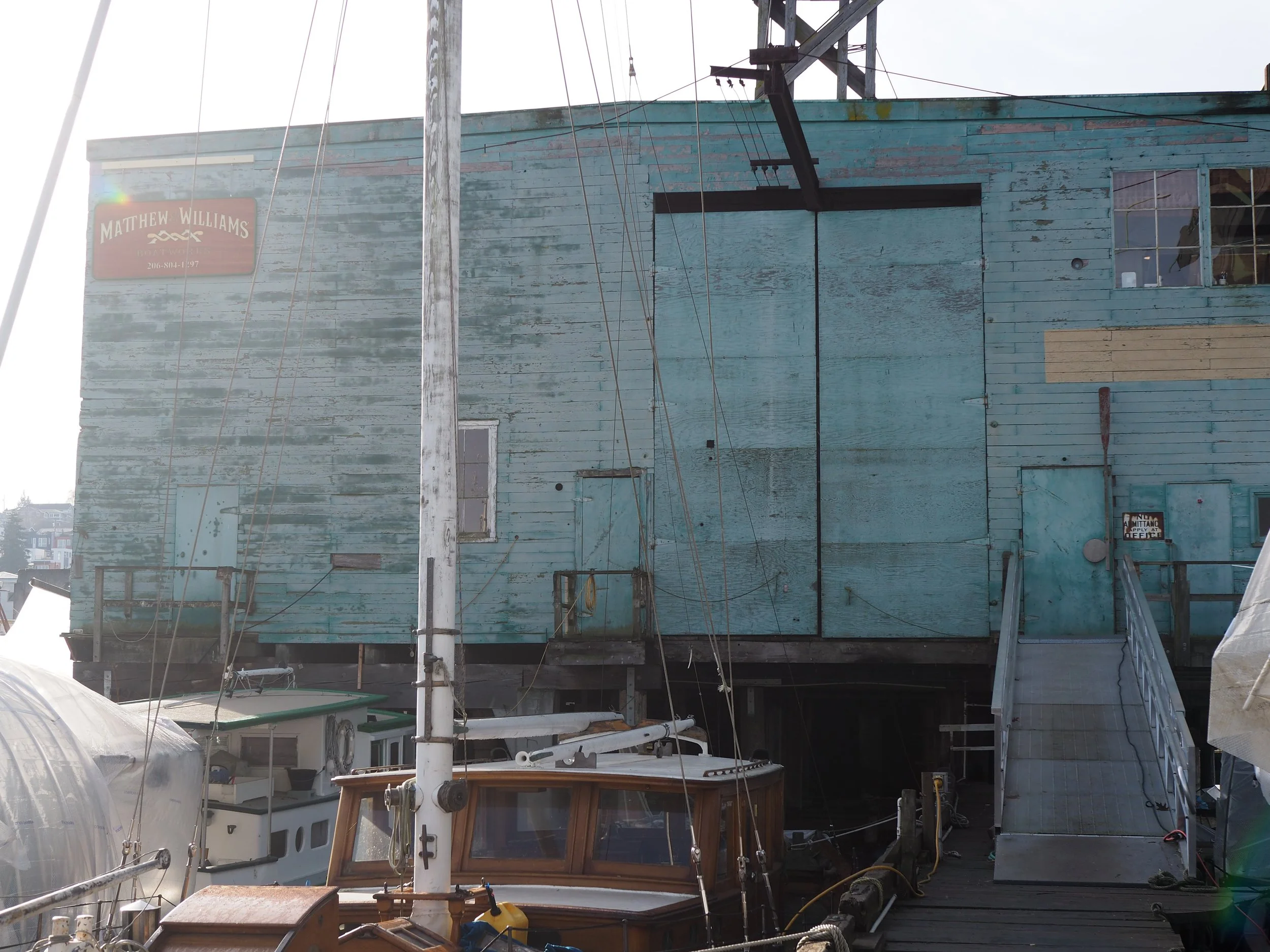 Exterior image of our green shop with business sign behind wooden boats.