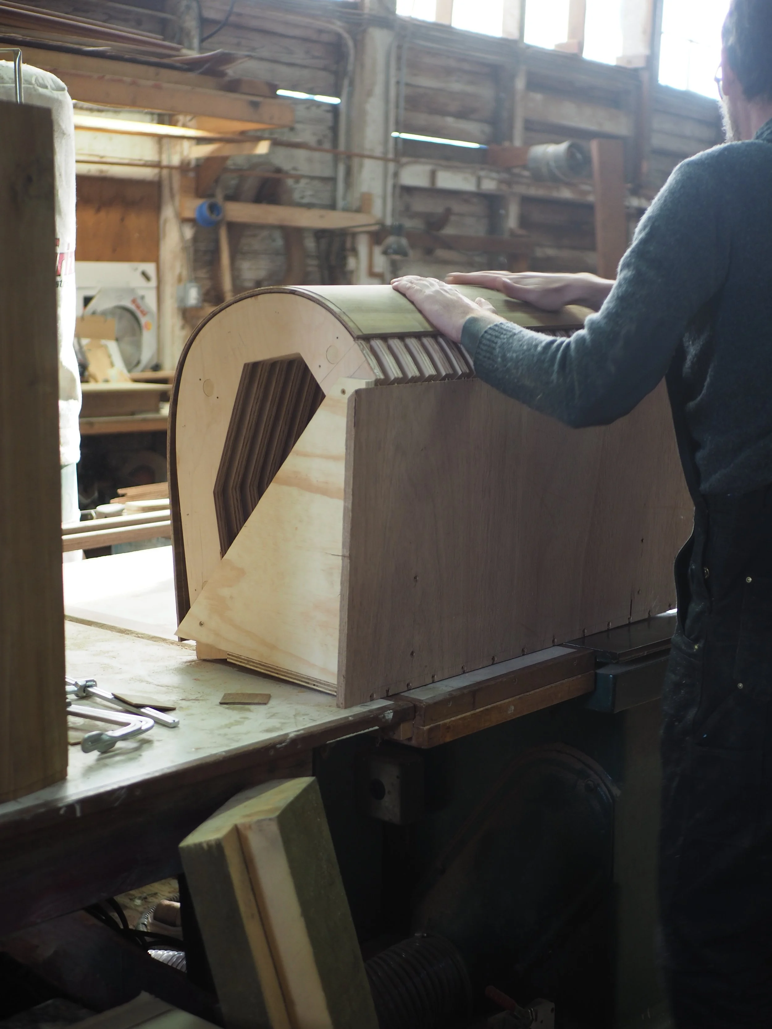Shipwright laminating teak plywood over jig for cabinetry project