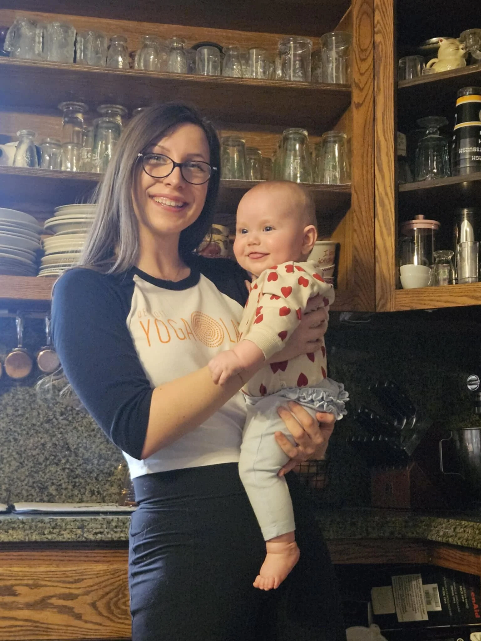 A young woman with long brown hair, wearing a white shirt, smiling at the camera against a plain background.