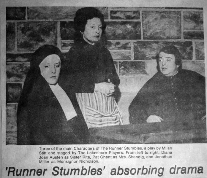 Black and white photo of three women on stage, with a brick wall backdrop. Left woman dressed as a nun, center woman standing with hands clasped, right woman seated. Caption notes they are characters from "The Runner Stumbles" playing for Lakeshore P