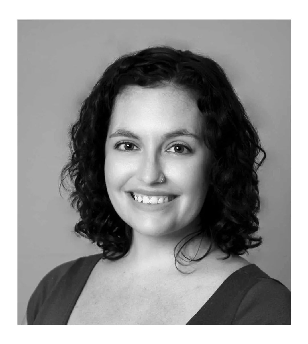 Black and white portrait of a woman with curly hair smiling at the camera.