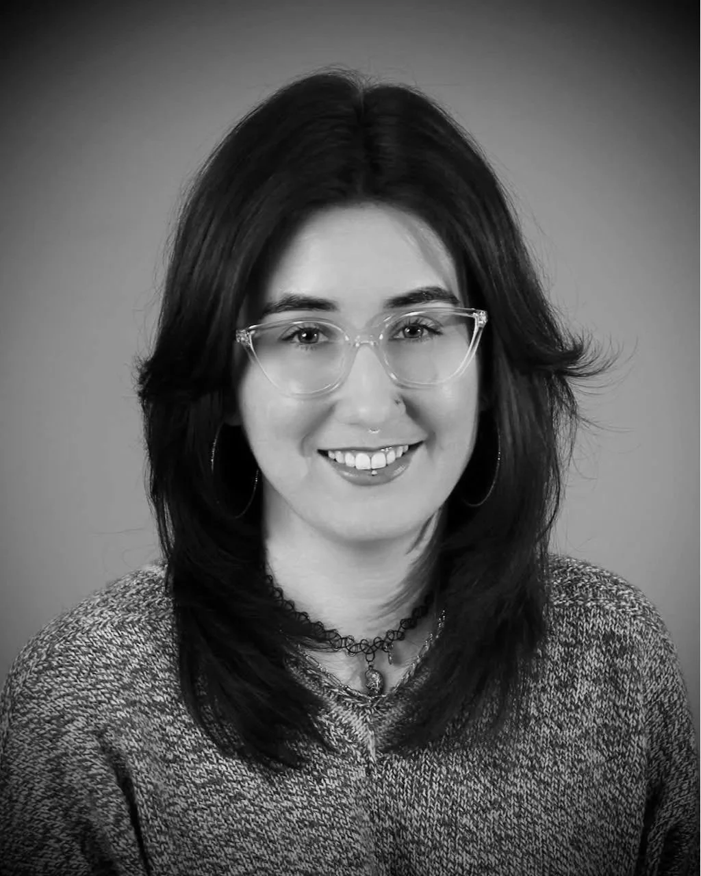 Black and white portrait of a woman with curly hair smiling at the camera.