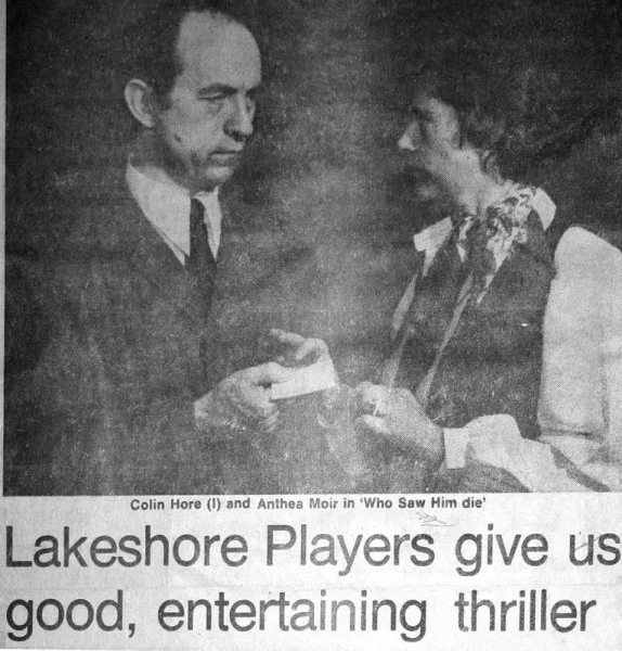Black and white photo of a man and woman facing each other, with the man holding papers and the woman appearing to receive or examine them. The caption below states names, Colin Hore and Anthea Moir, from the play 'Who Saw Him Die'.