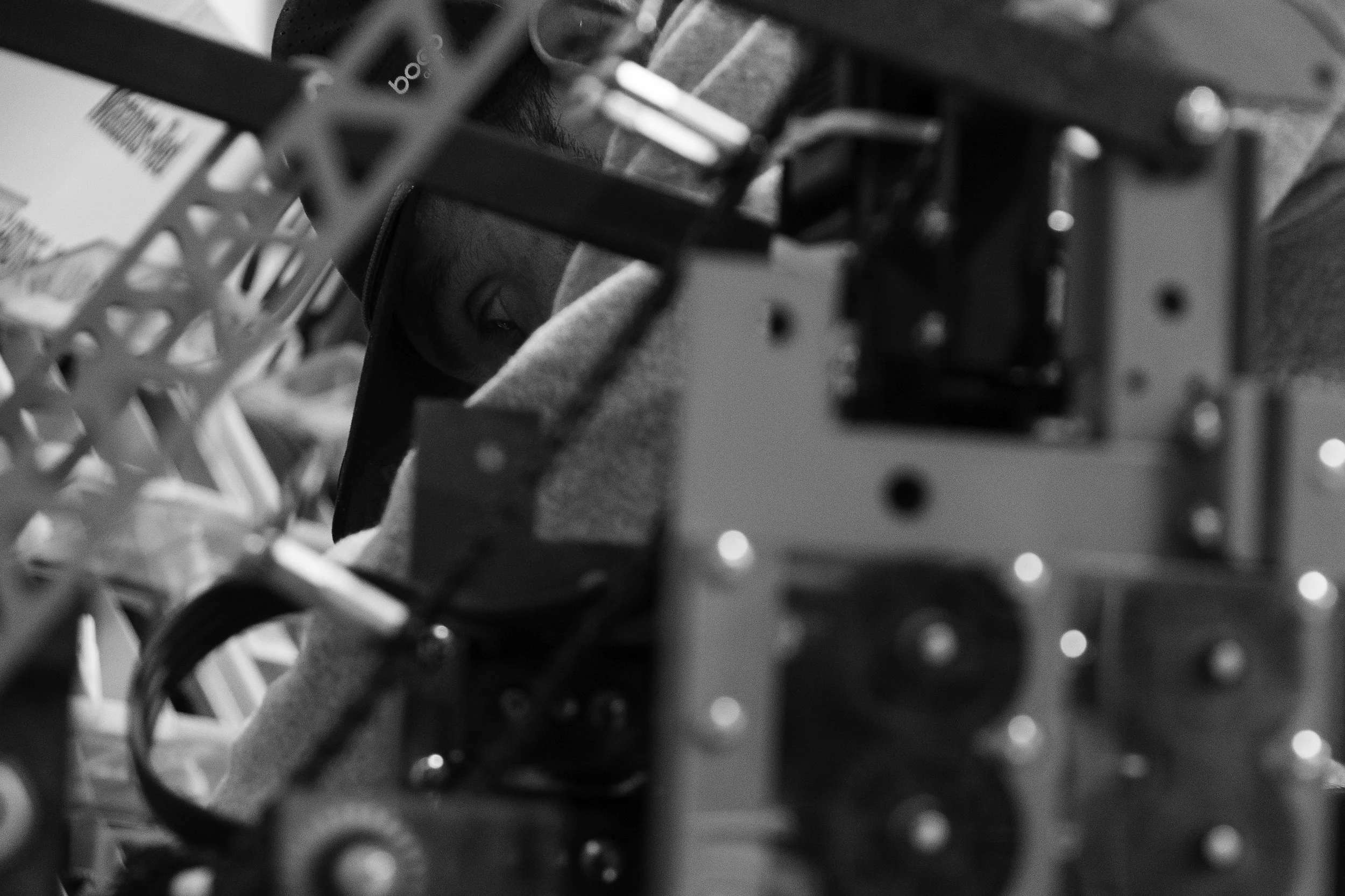 A person operating or inspecting a complex mechanical or electronic device with various circuit boards and components, partially obscured by the structure of the device.