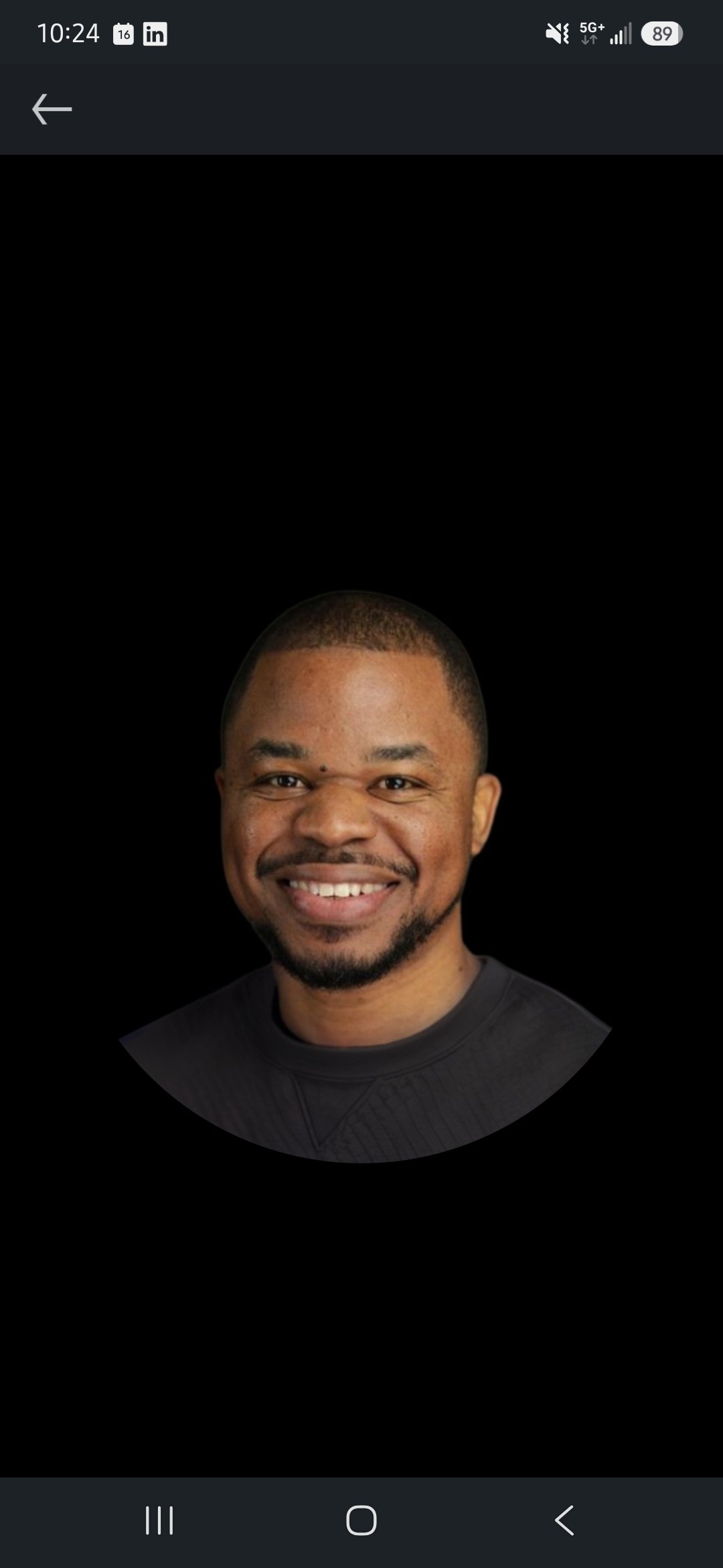 A man wearing a black beanie and black jacket, smiling against an orange background.