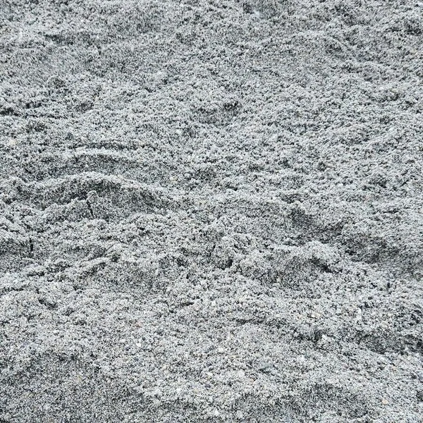 Close-up of sand with visible footprints and uneven texture.