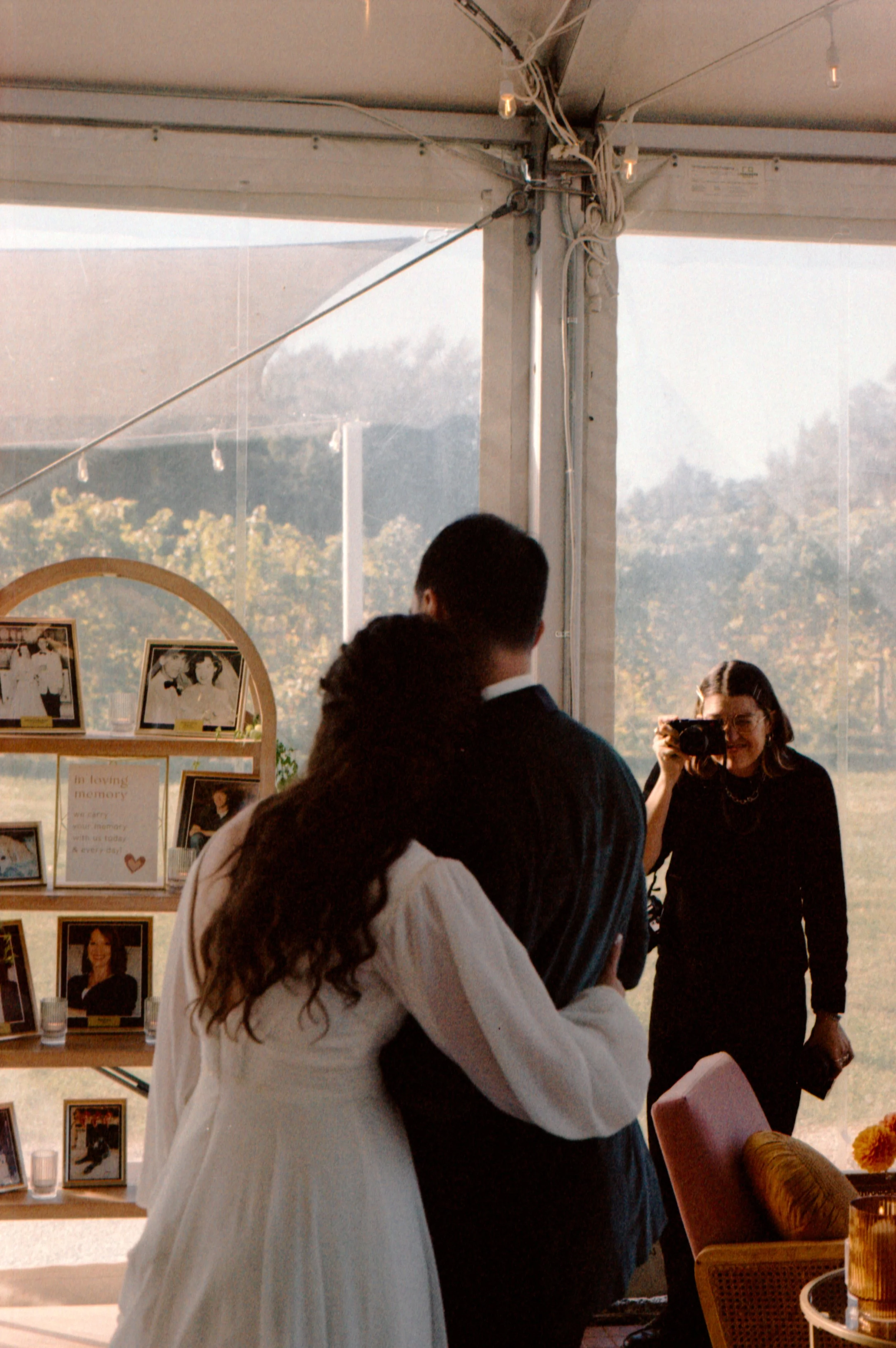 LBW82-bride-hugging-groom-look-at-family-photos-wedding.jpg