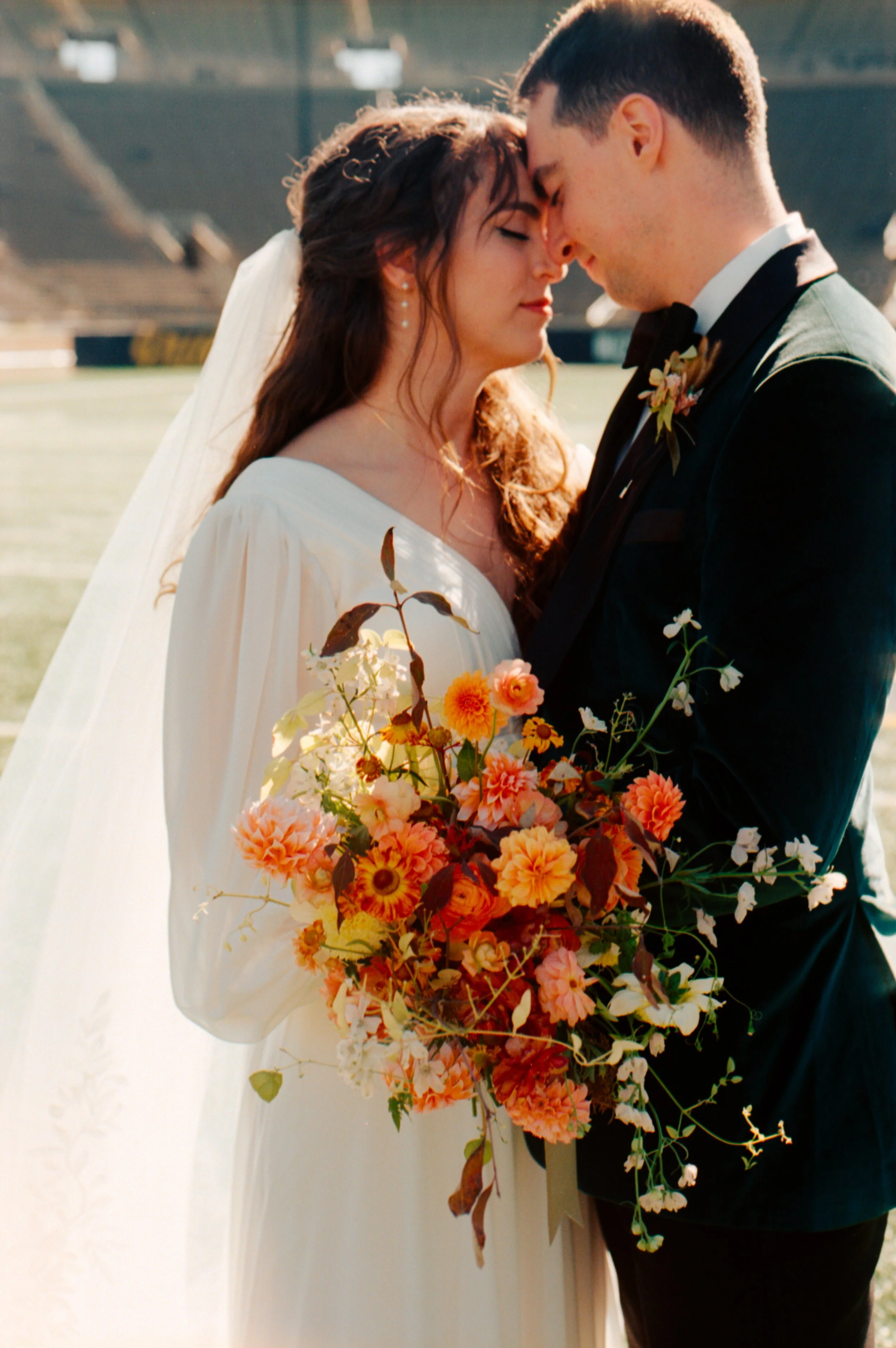 LBW52-wedding-couple-holding-flowers-foreheads-together.jpg
