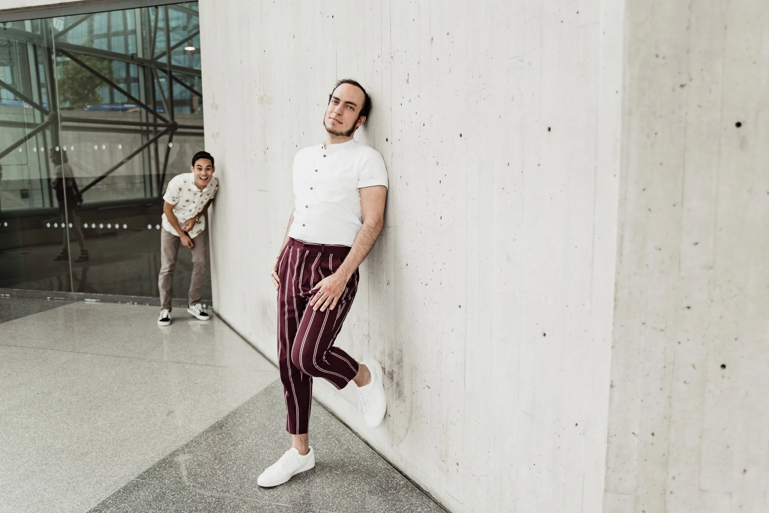 BT305-man-leaning-against-wall-with-man-in-background.jpg