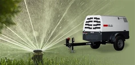 A portable irrigation sprinkler connected to a water source, watering a grassy area.