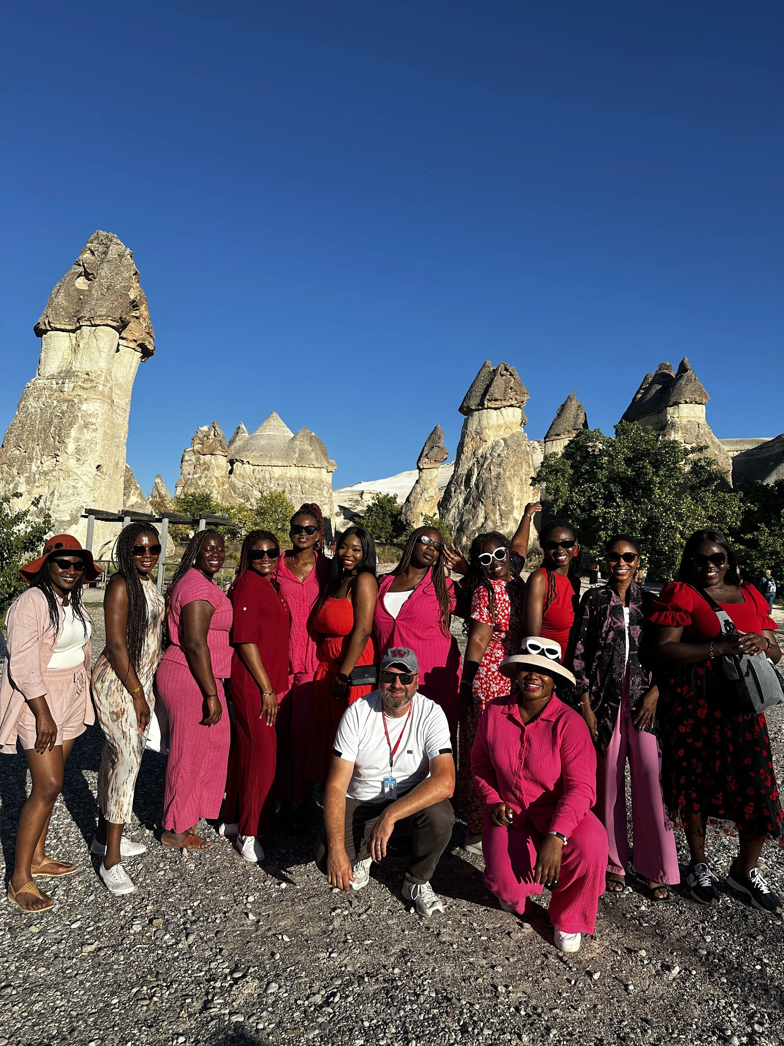 Group of people in colorful clothing posing in front of rock formations under blue sky